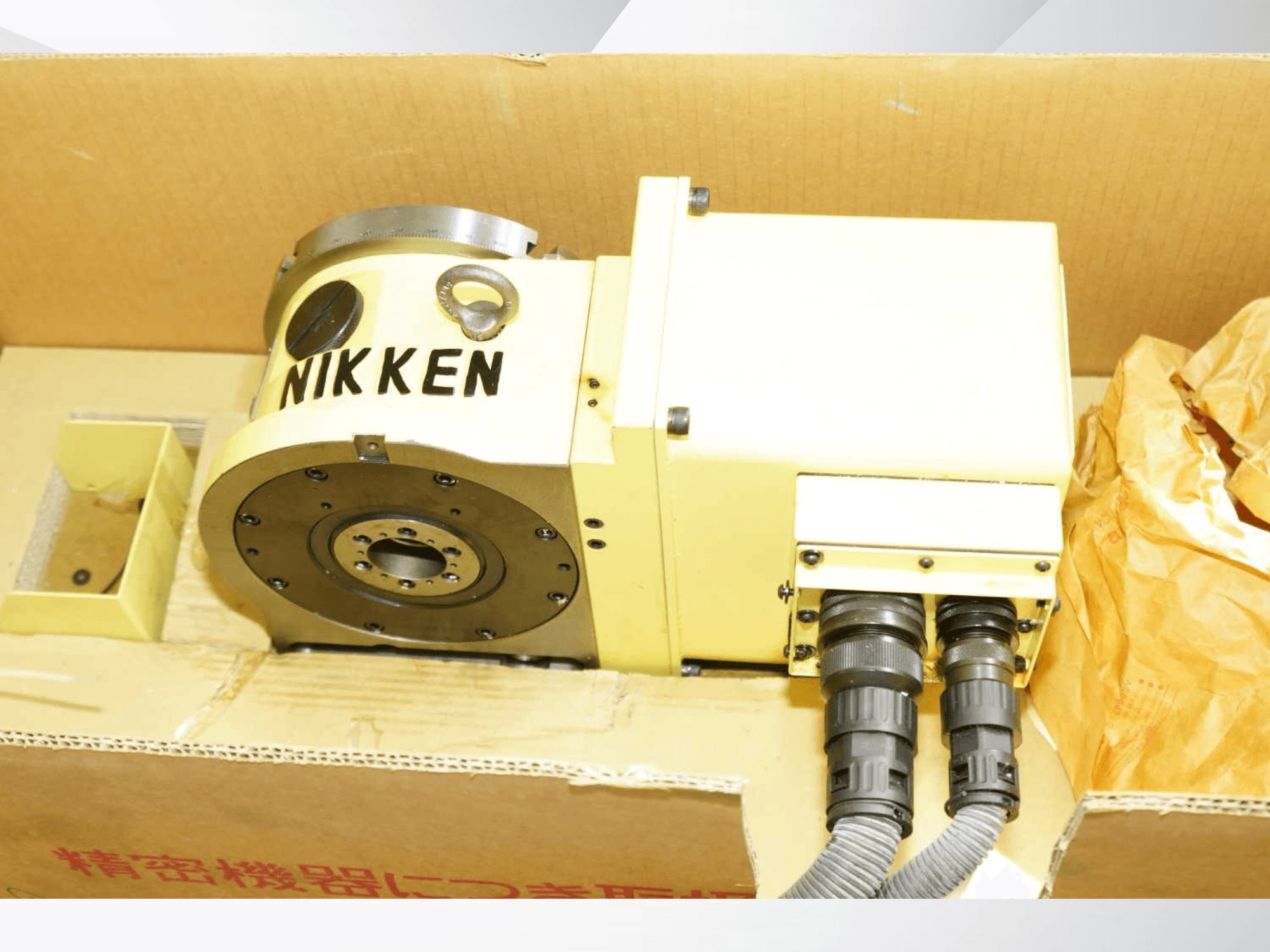 NIKKEN rotary table in yellow with connectors, front view, showcasing machining components for precise operations.