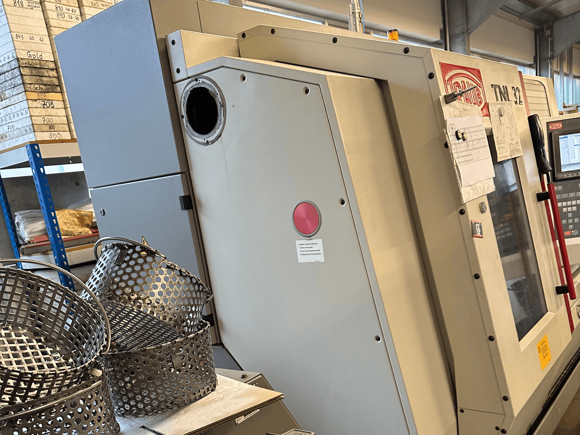 TRAUB TNL 32 P Swiss Type Turning Machine in a side view, with factory baskets visible in the foreground.