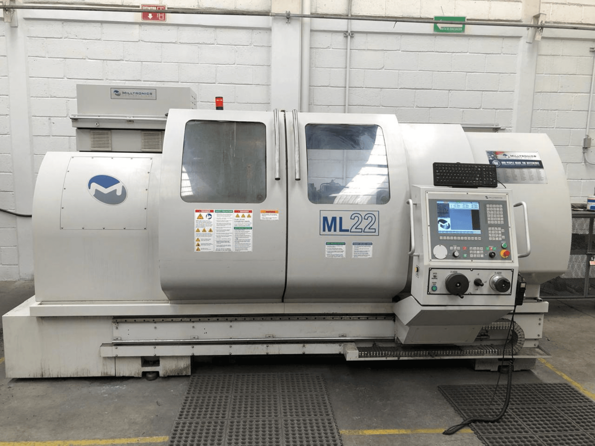 Vertical Machining Centre MILLTRONICS RH 20, front view showing control panel, brand logo, and safety labels on the machine.