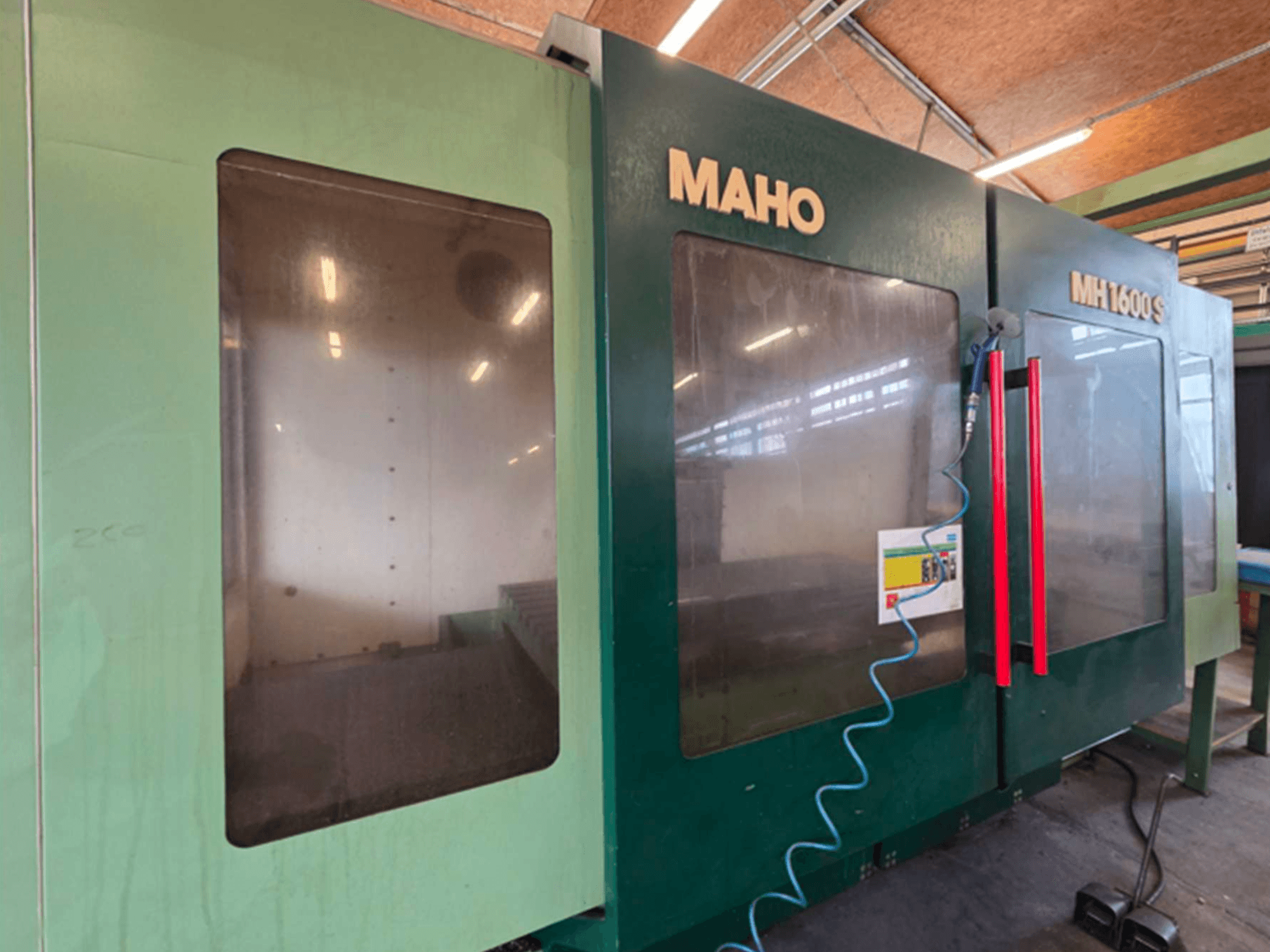 Front view of MAHO 1600S Universal Machining Centre, featuring dual transparent panels and control panel with red handles.