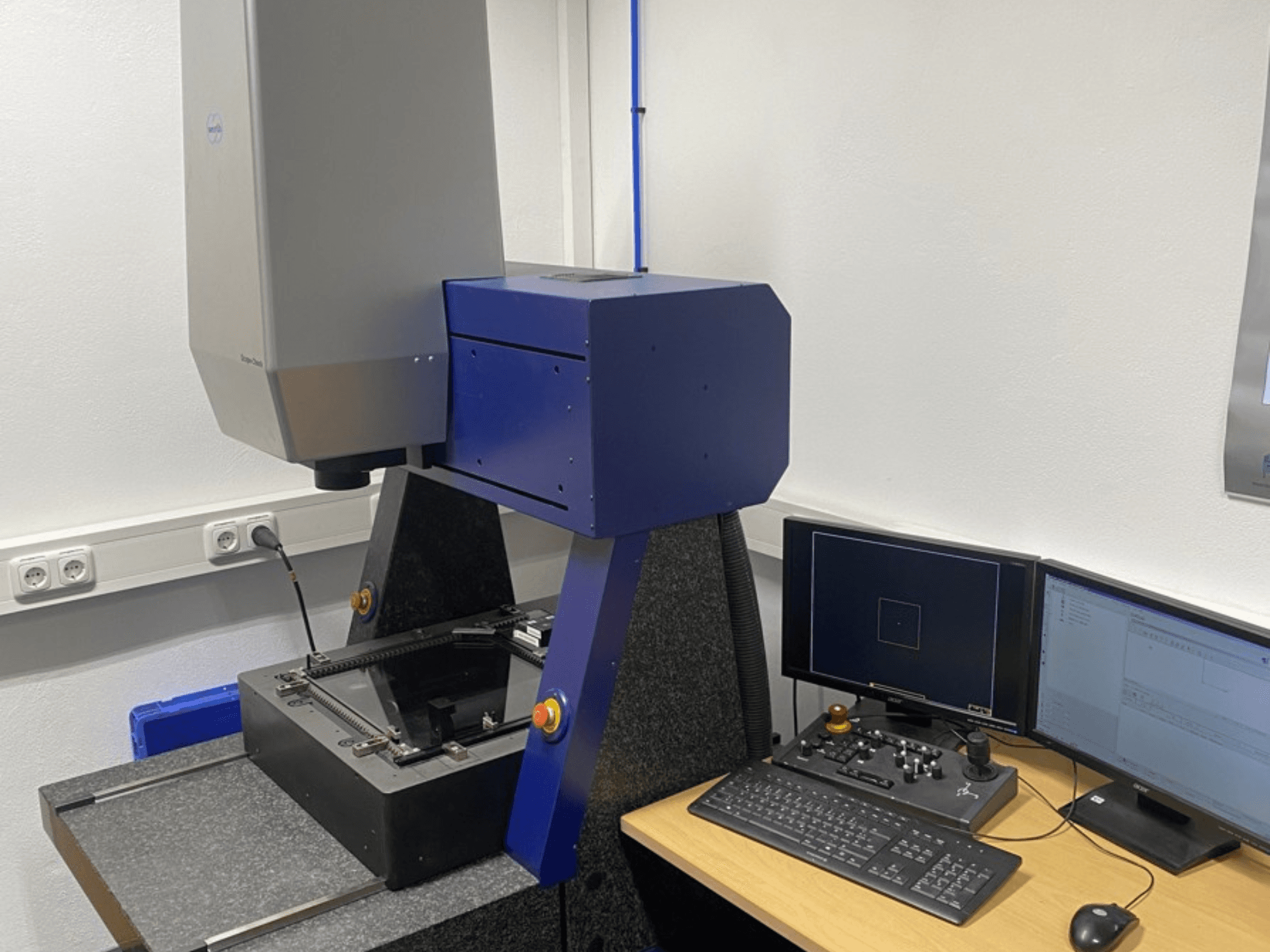 Werth Scope-Check 400 CMM in a lab, showing the measuring head and control panel with screens and keyboard.