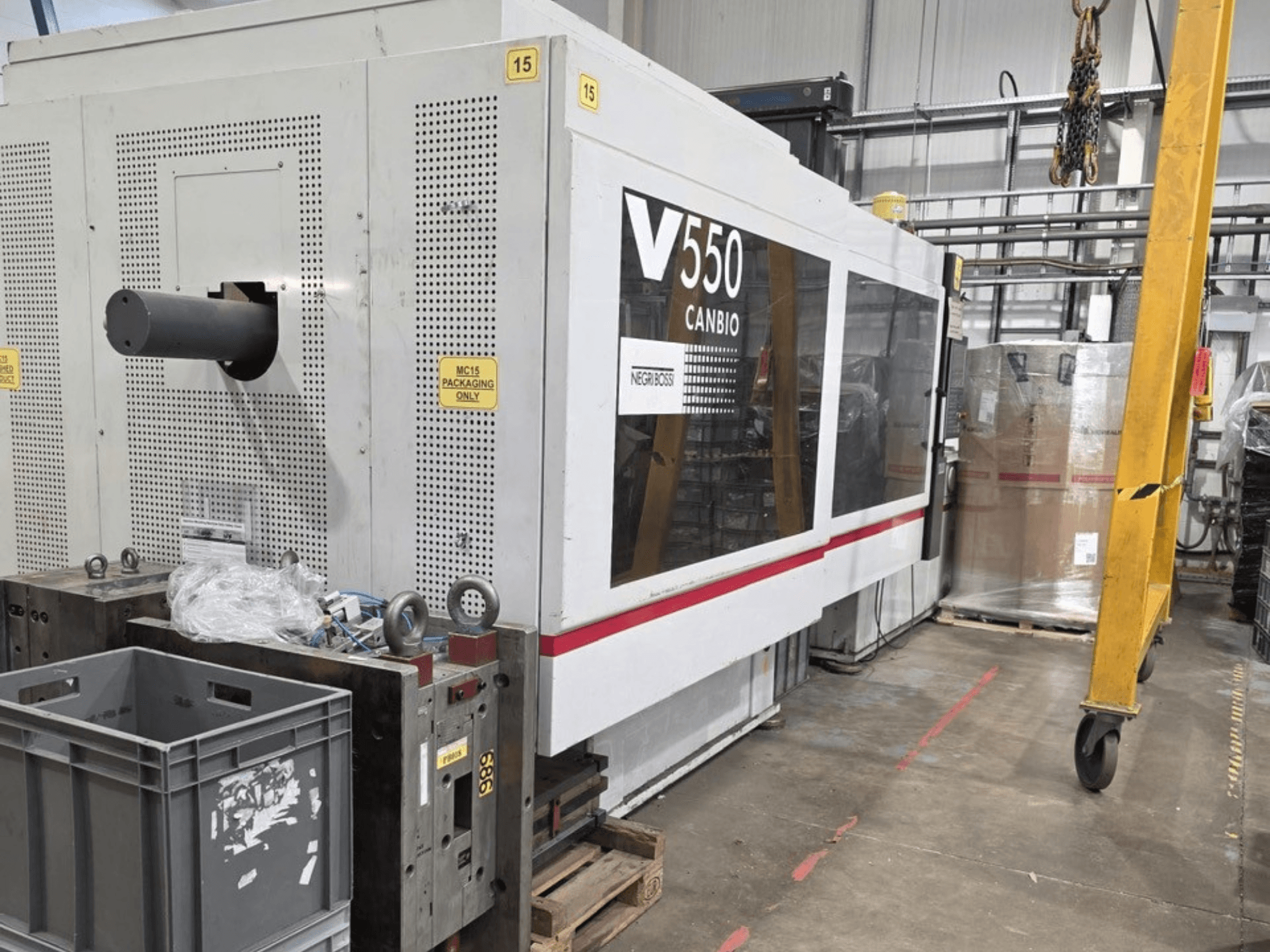 Negri Bossi V55000H-4250 hydraulic injection moulding machine, side view, featuring control panel and grey crates in foreground.