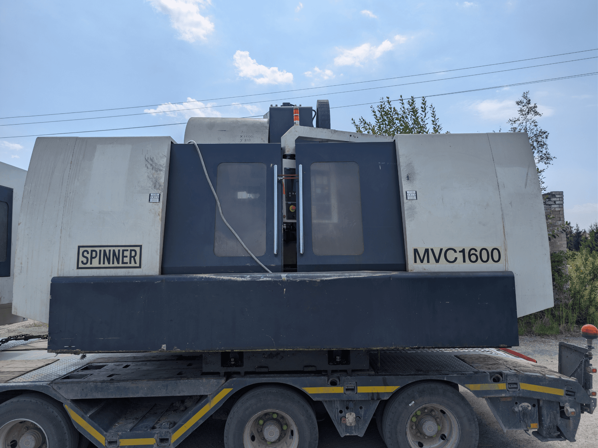 SPINNER MVC 1600 vertical machining centre, front view on a truck, showcasing branding and large machining area.