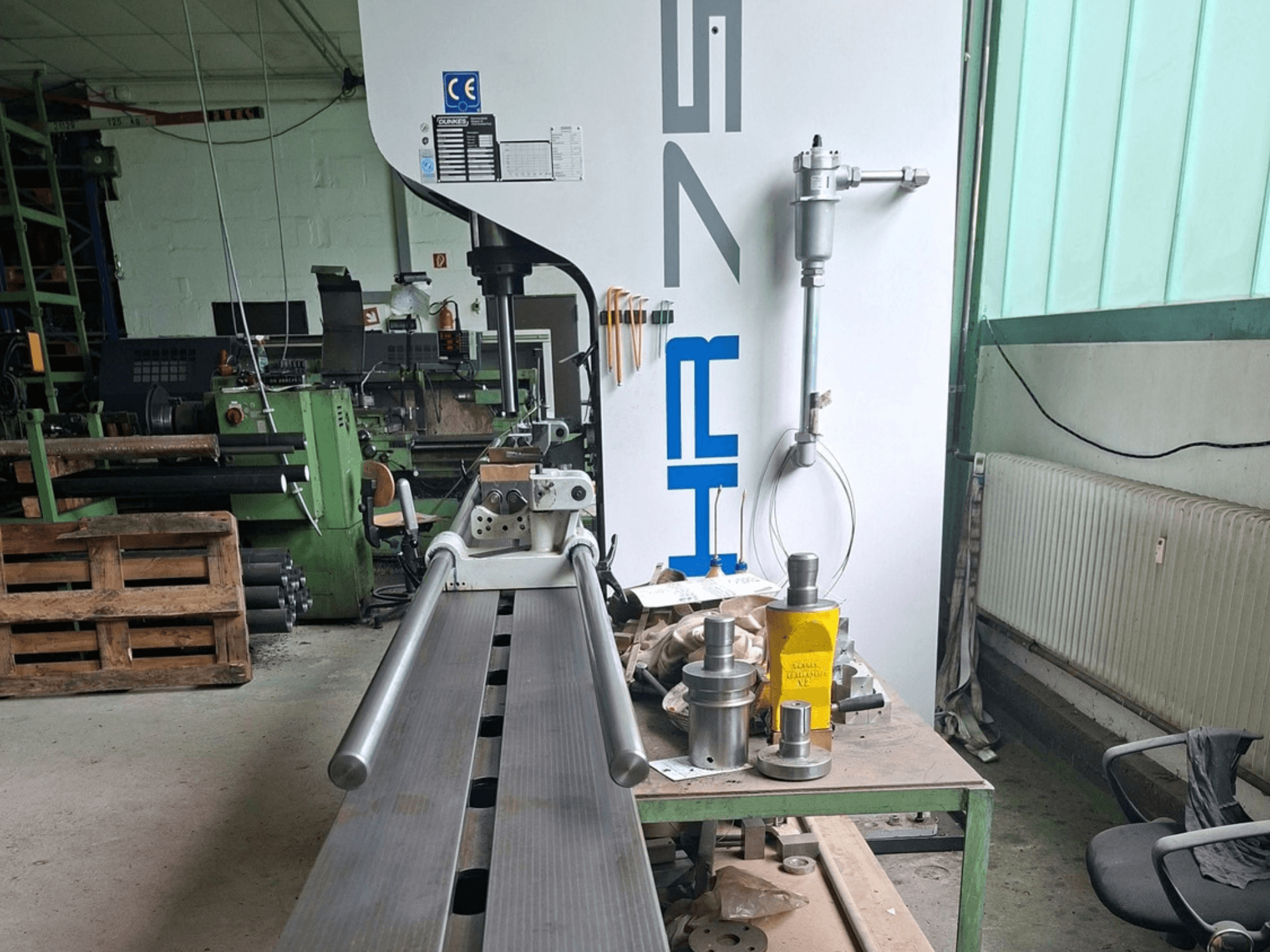 Dunkes HR75 metal press in workshop, side view showing profile and surrounding tools on table.