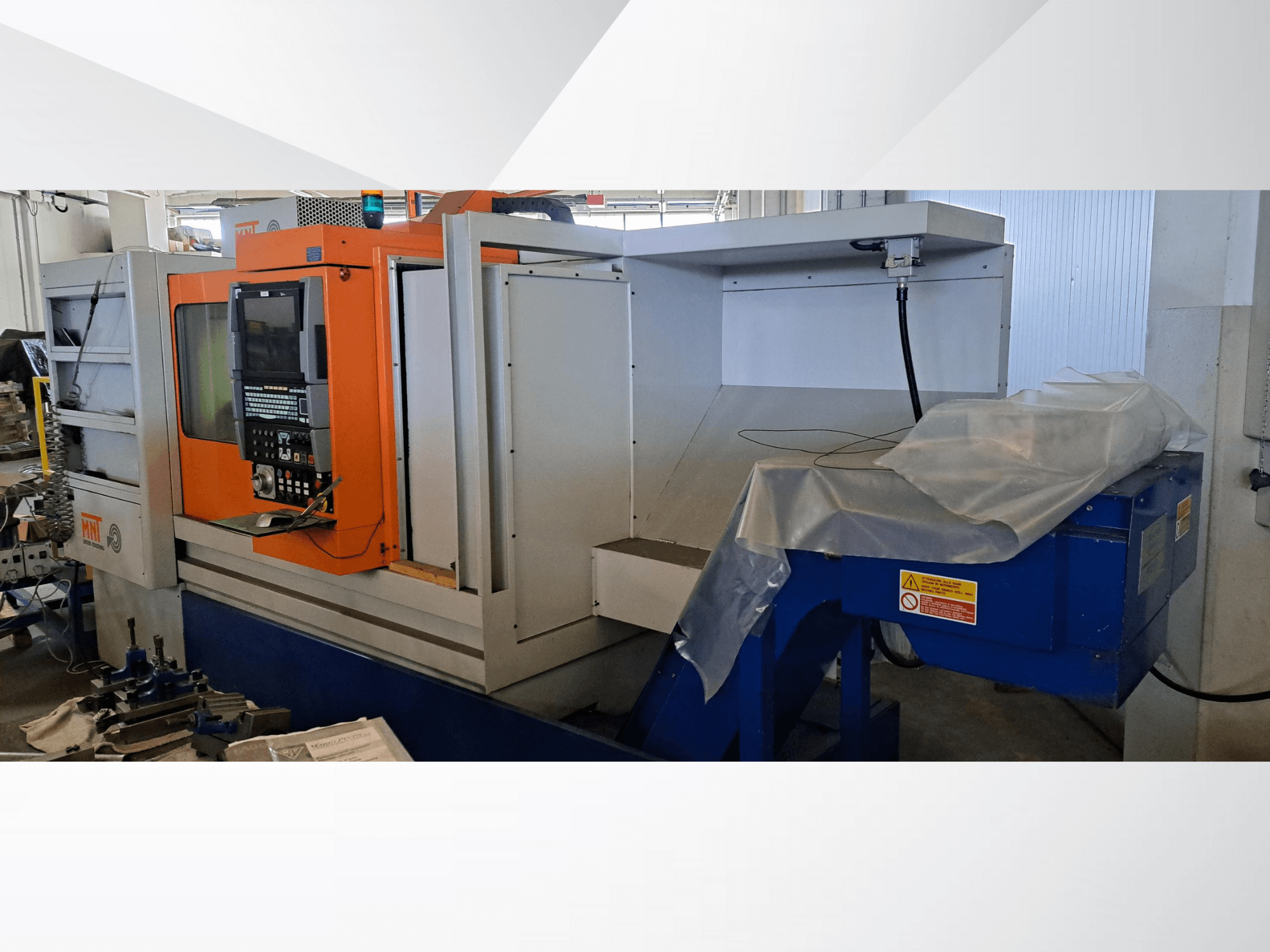 MNT CNC machine, front view, featuring orange control panel, large machining area, and blue chip disposal unit.