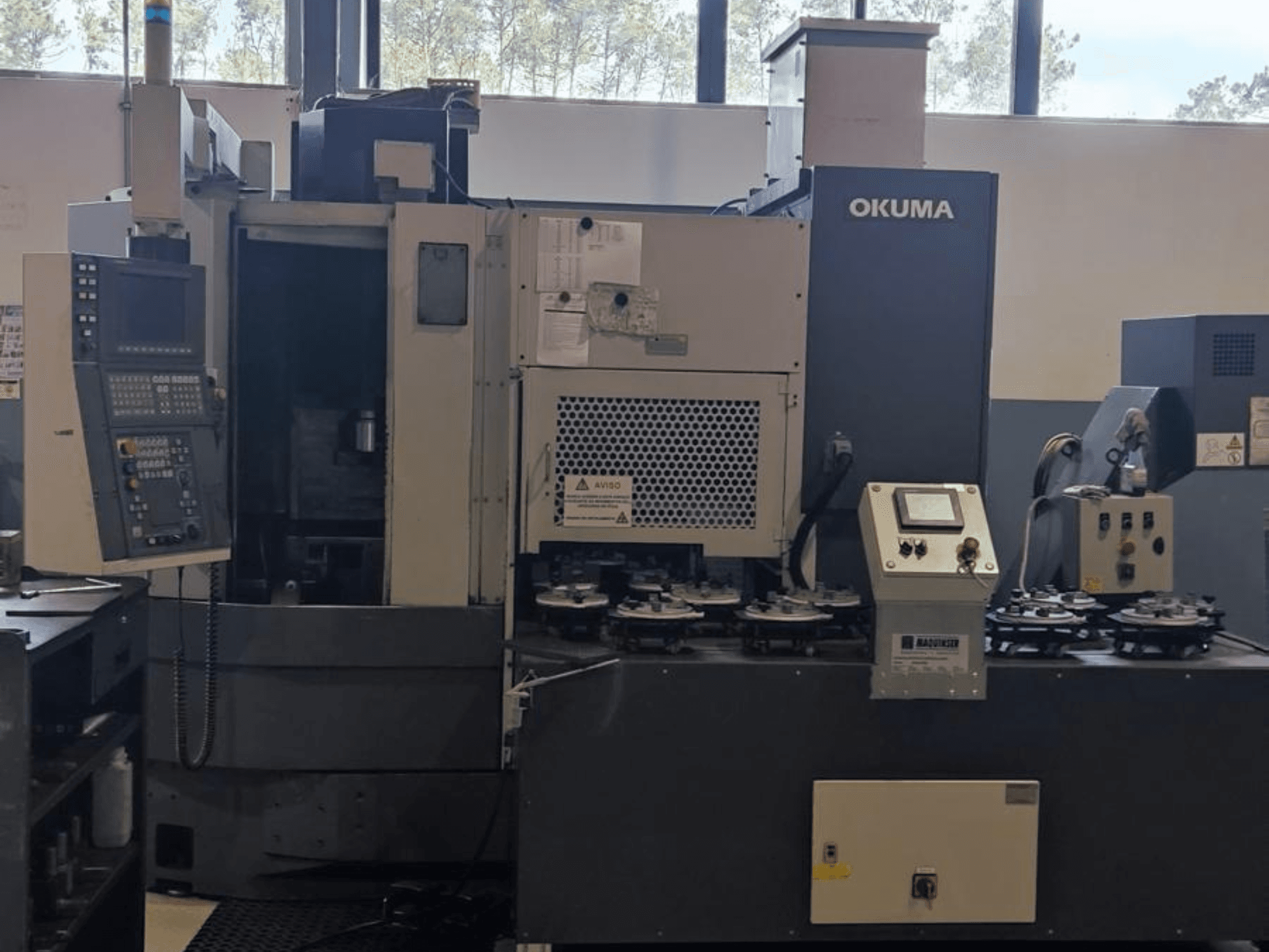 Okuma LVT300 vertical turning machine in a front view, featuring control panel, tool holders, and machining area.