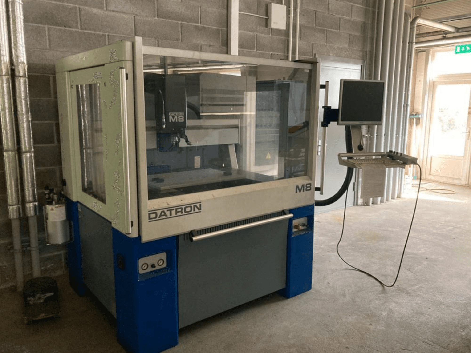 Datron M8A vertical machining center in a workshop, front view with control panel and touchscreen monitor.