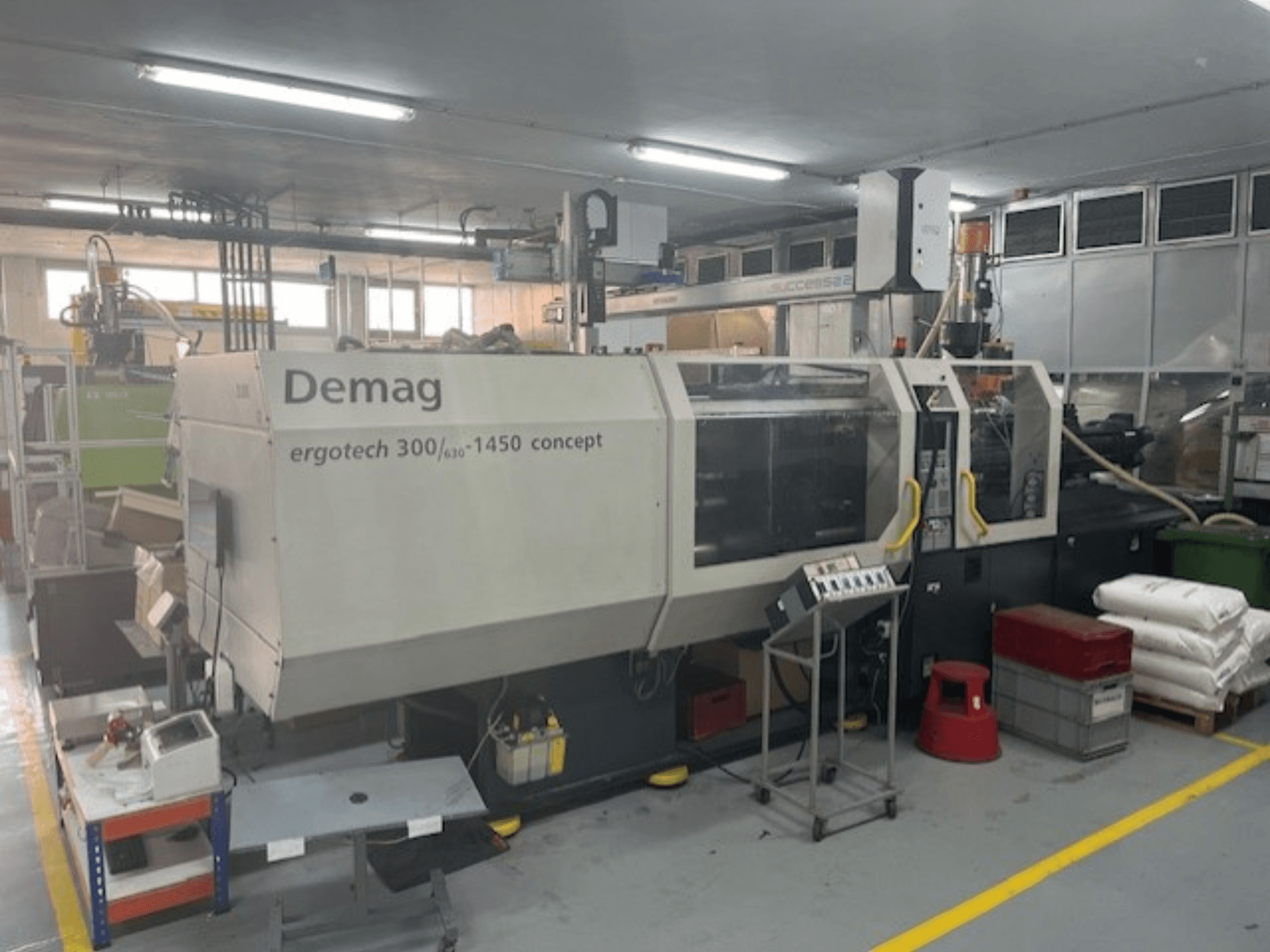 Demag ERGOTECH CONCEPT 3000-1450 hydraulic injection moulding machine, front view, with operational controls and materials nearby.