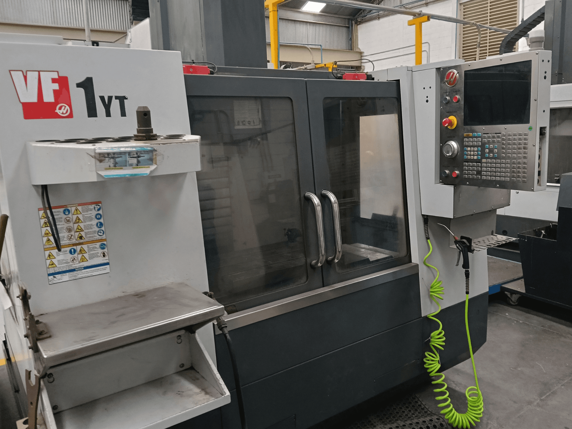 HAAS VF-1YT-2 Vertical Machining Centre, front view, showing control panel, tool holder, safety labels, and machining area.