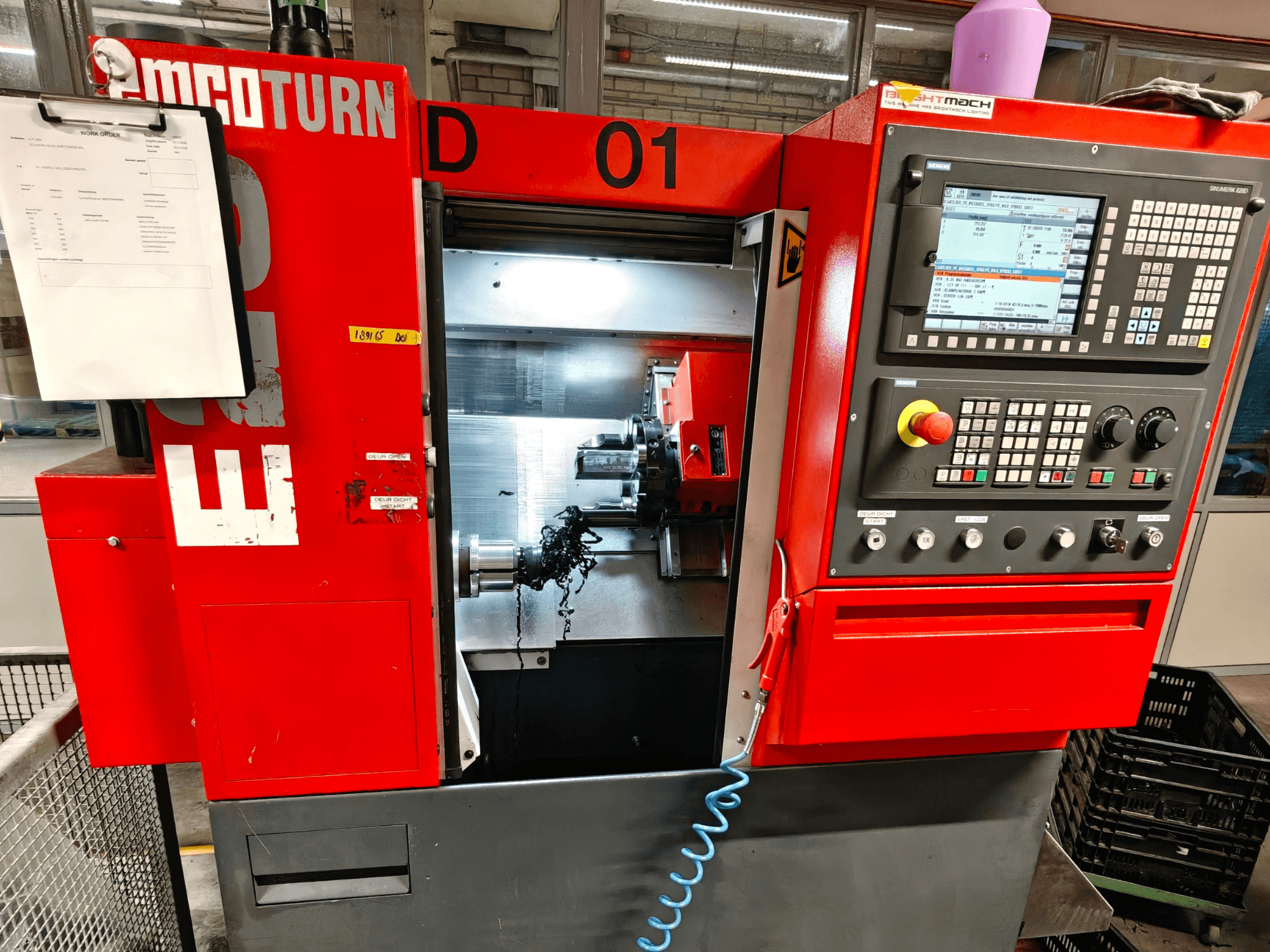 Front view of EMCO TURN E25 horizontal turning machine, featuring operational controls, tool holder, and work area with chippings.