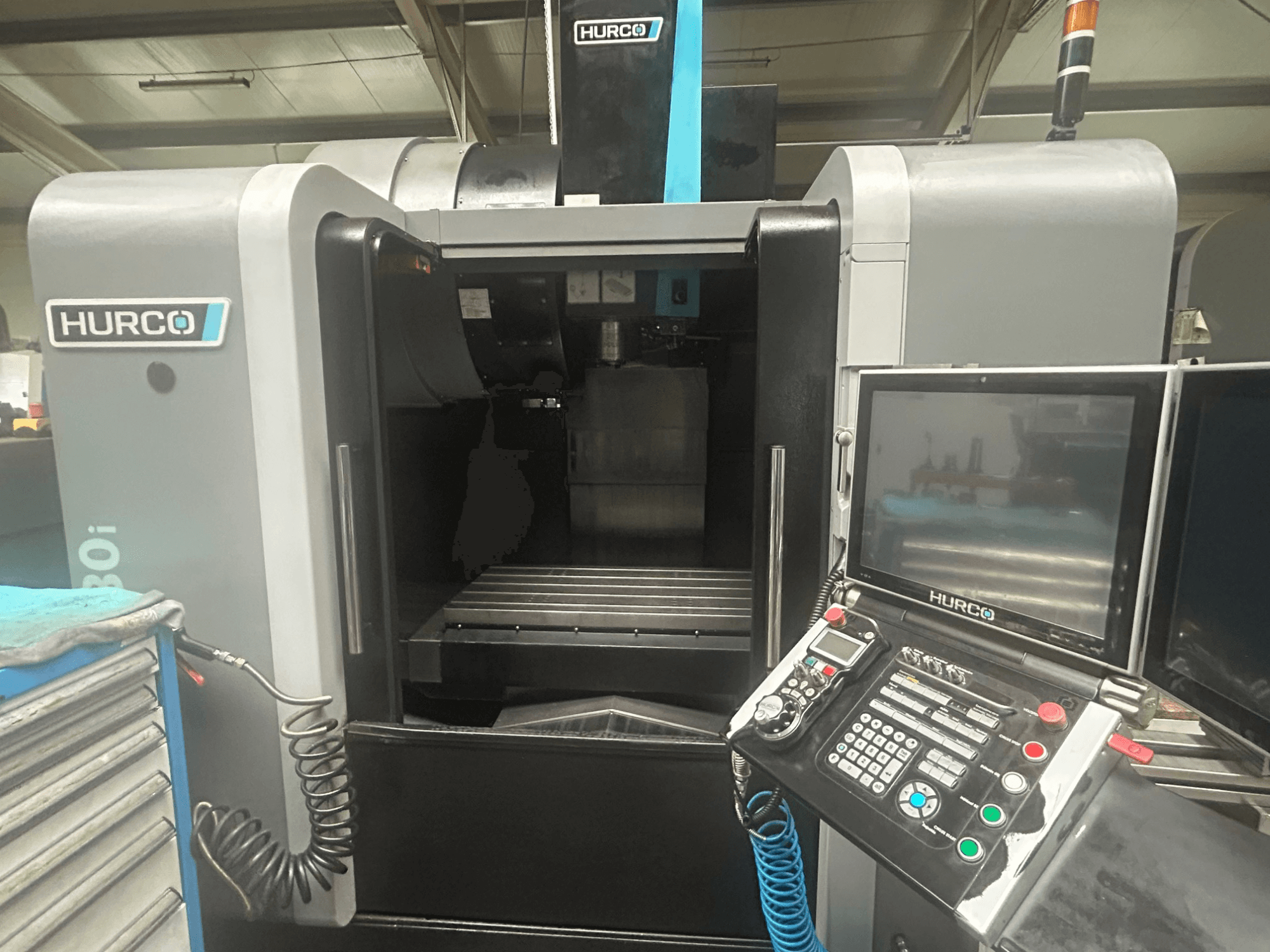 Hurco VM30i CNC machine front view, featuring control panel with buttons, display, and tool storage area.