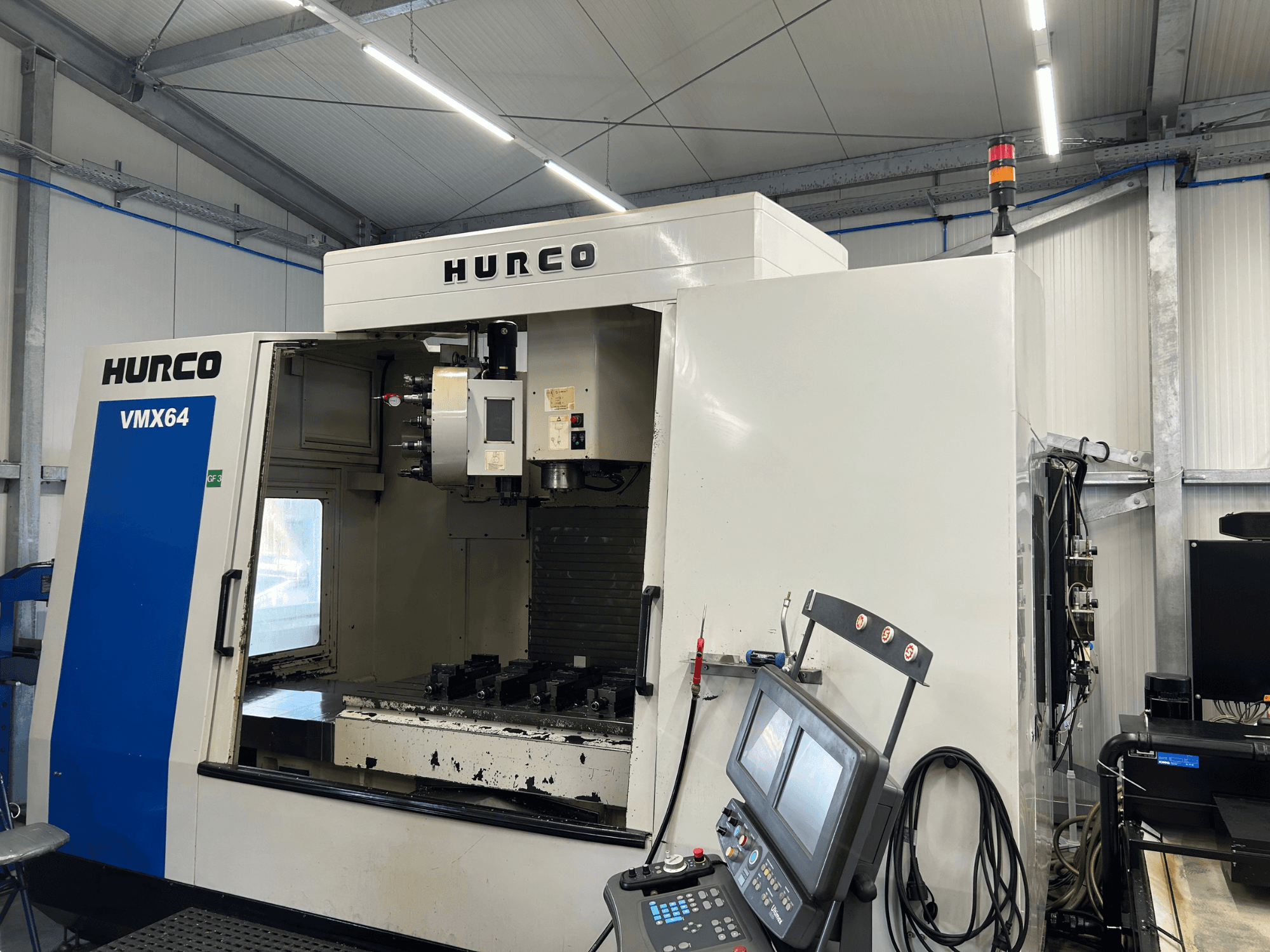 Hurco VMX 64 vertical machining center, front view, showcasing the control panel and open workspace with tools.
