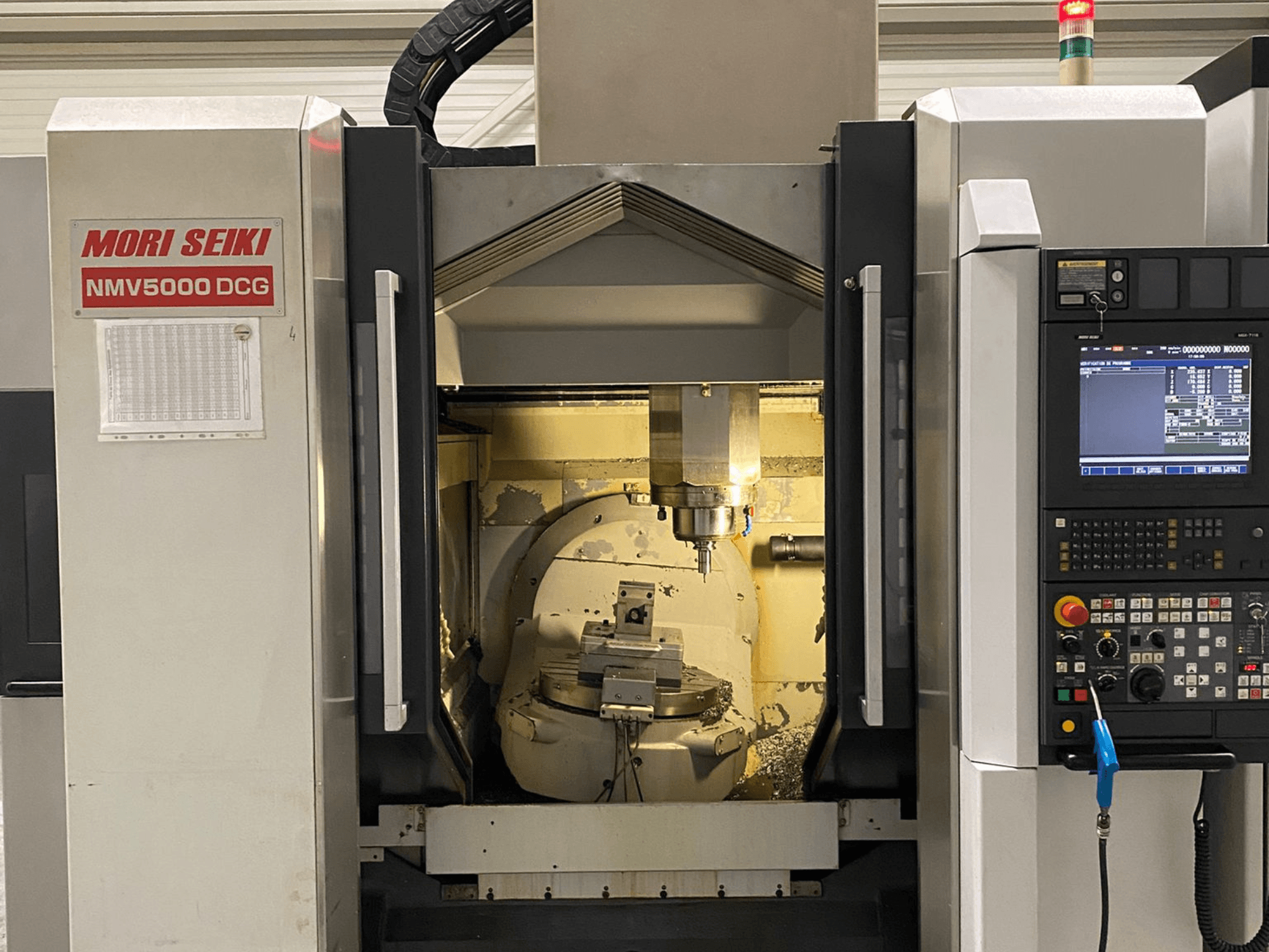 MORI SEIKI NMV 5000DCG universal machining center, front view showing control panel and interior machining area.