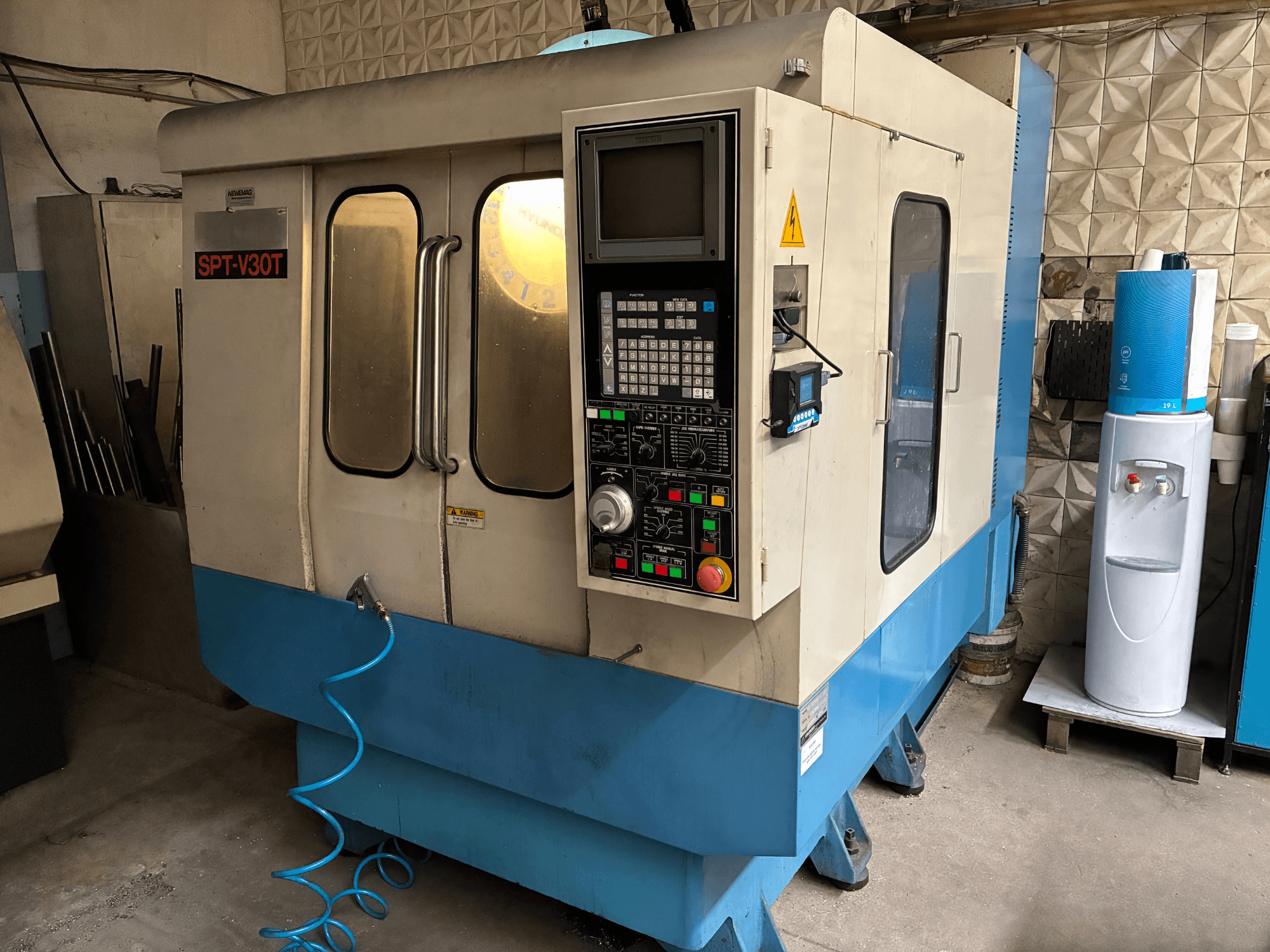 SPT-V30T CNC machine in blue and white, front view showing control panel, doors, and air hose. Perfect for precision machining.