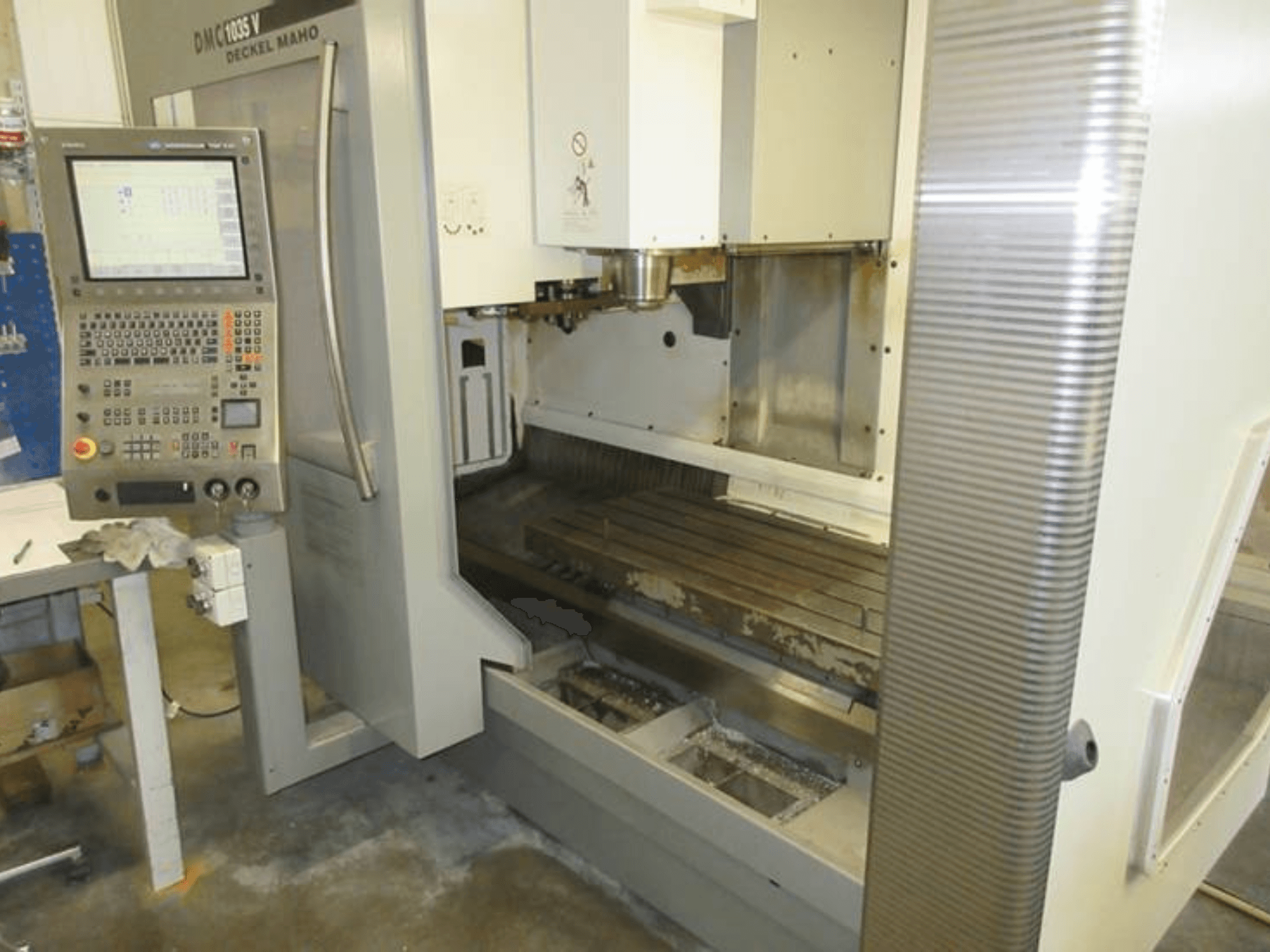 Front view of DECKEL MAHO DMC 1035 V vertical machining center with control panel, visible worktable, and spindle area.