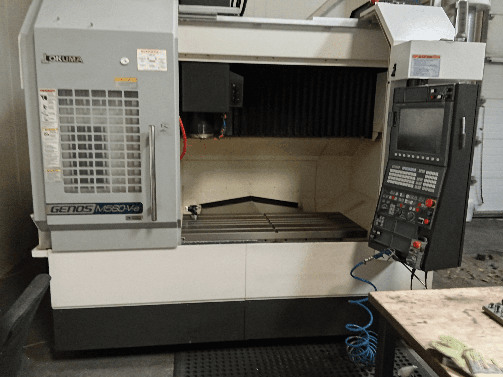 Okuma GENOS M560-V, front view of a vertical machining center with control panel, CNC interface, and visible cutting area.