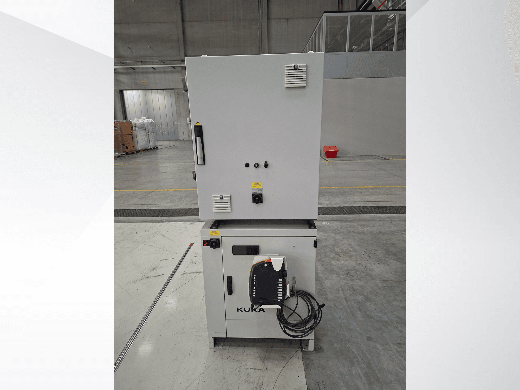 KUKA KR 90 R2700 PRO C4 FLR robot arm controller, front view showing control panel and safety labels in a spacious warehouse.