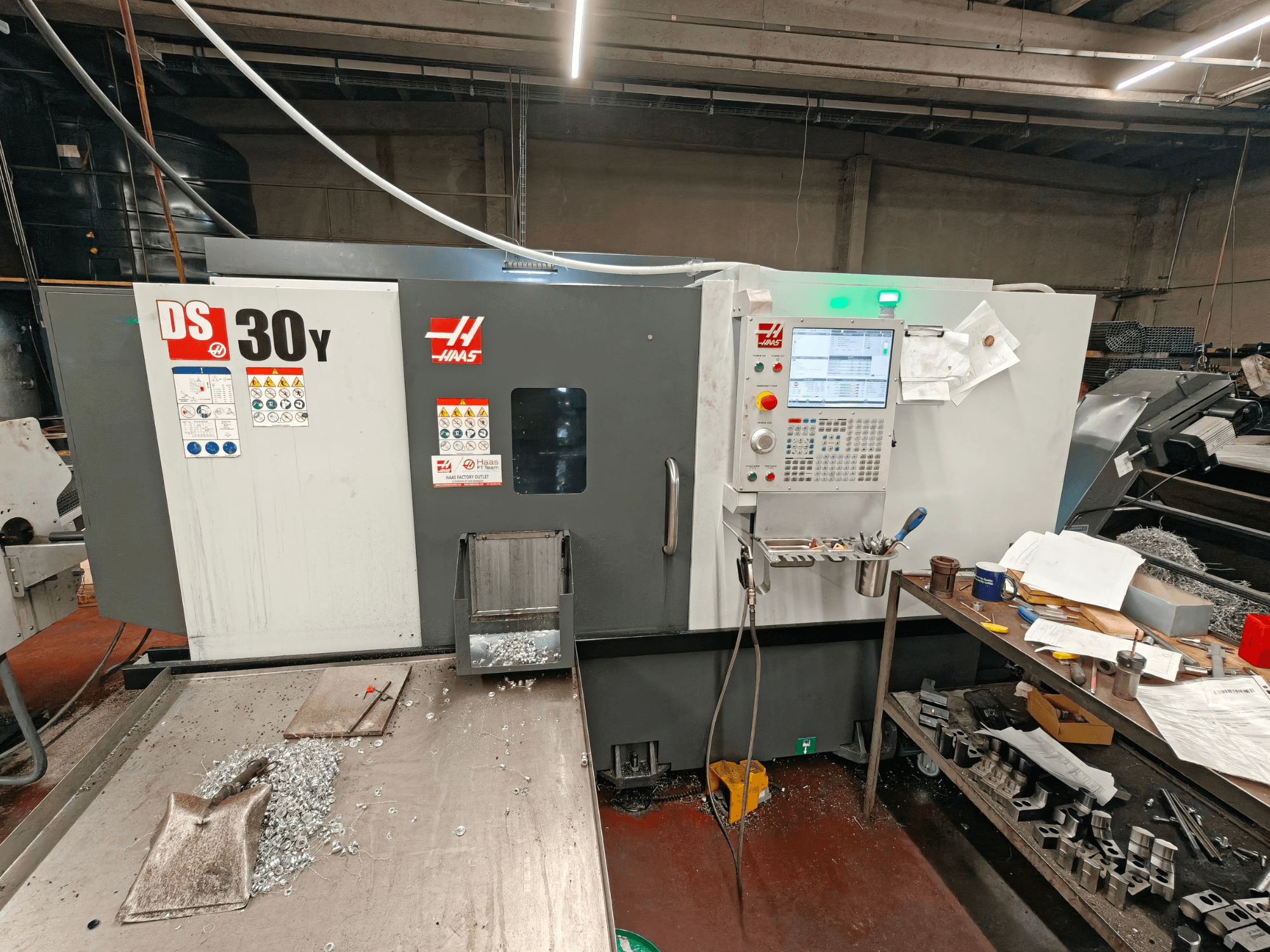 HAAS DS30Y horizontal turning machine in a workshop, front view showing control panel and metal shavings on the surface.