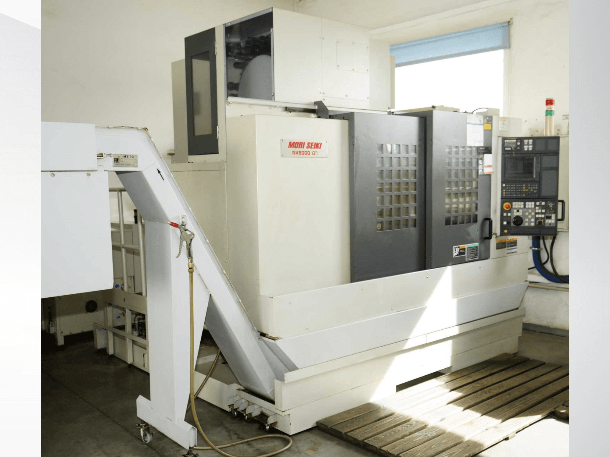 MORI SEIKI NV 5000 alpha1 vertical machining center in front view, showcasing control panel, safety features, and loading area.