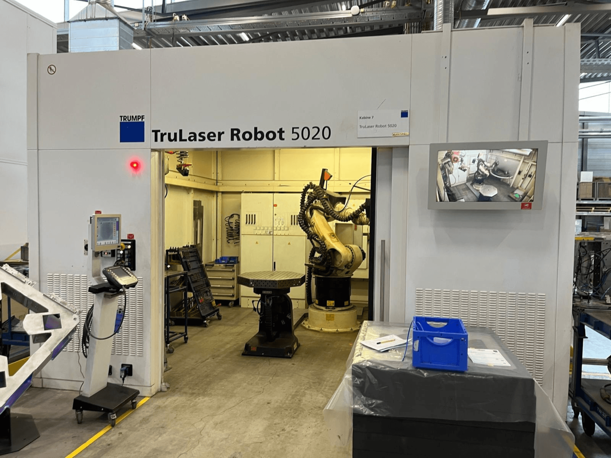 TRUMPF TruLaser Robot 5020 in an industrial setting, featuring controls, a robotic arm, and a monitor displaying operations.