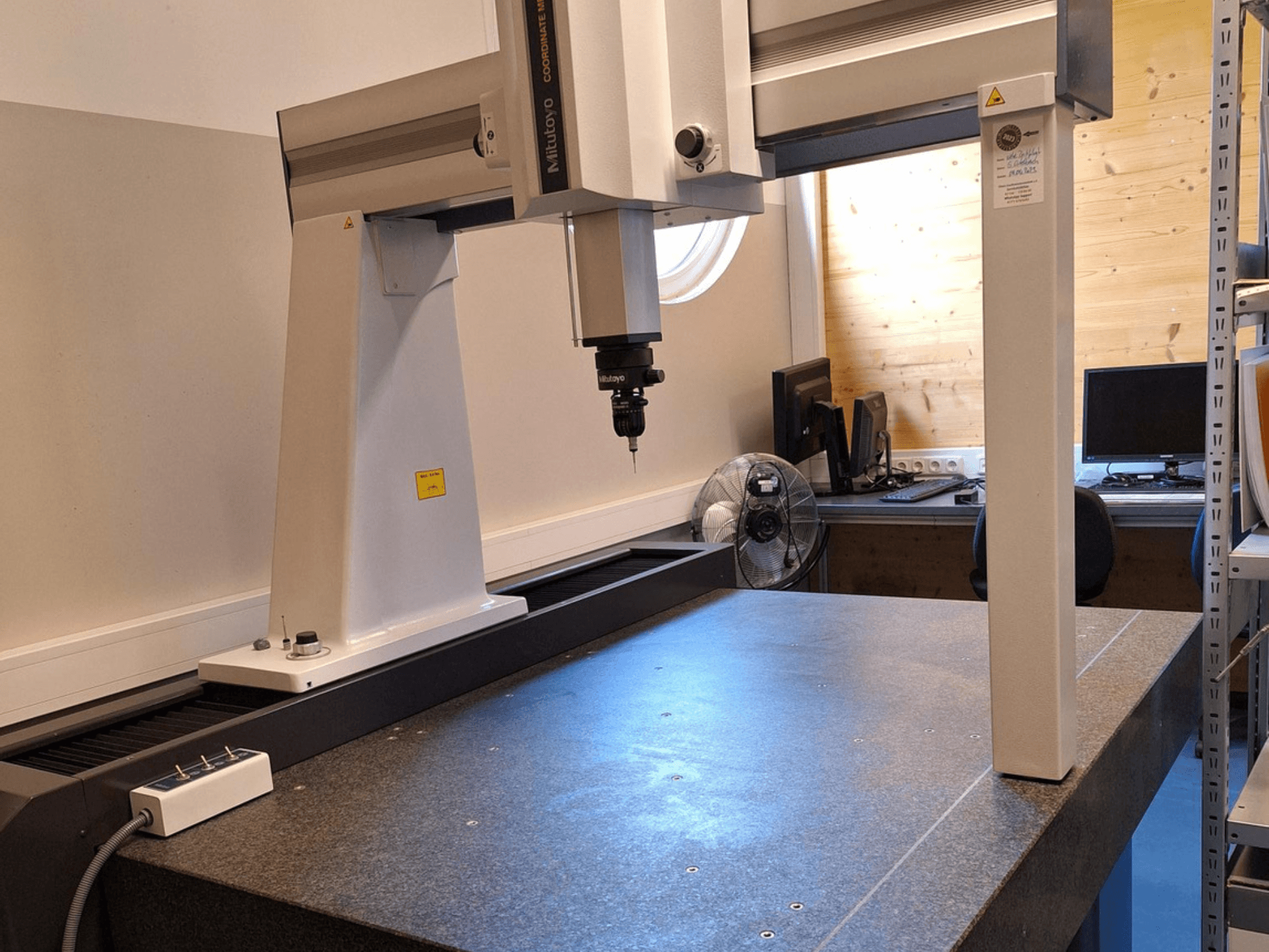 Mitutoyo Crysta-Plus M7106 gantry robot in a workshop, front view, showcasing measurement probe and granite surface plate.
