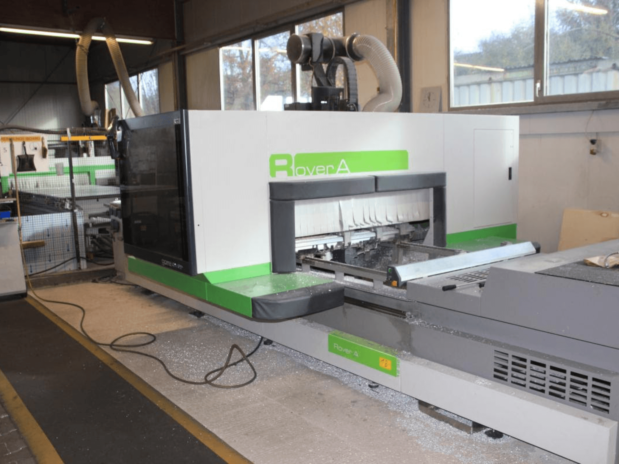 BIESSE Rover A 1232 CNC router, side view showing the cutting area and control panel in an industrial setting.