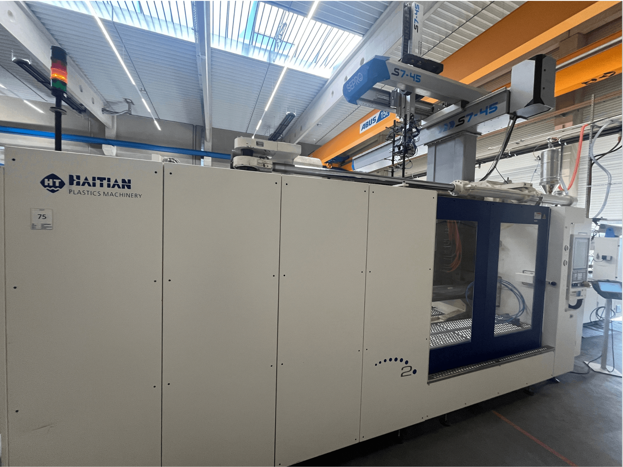 Haitian S7-45 injection molding machine in side view with control panel and safety light indicator. White and blue design.