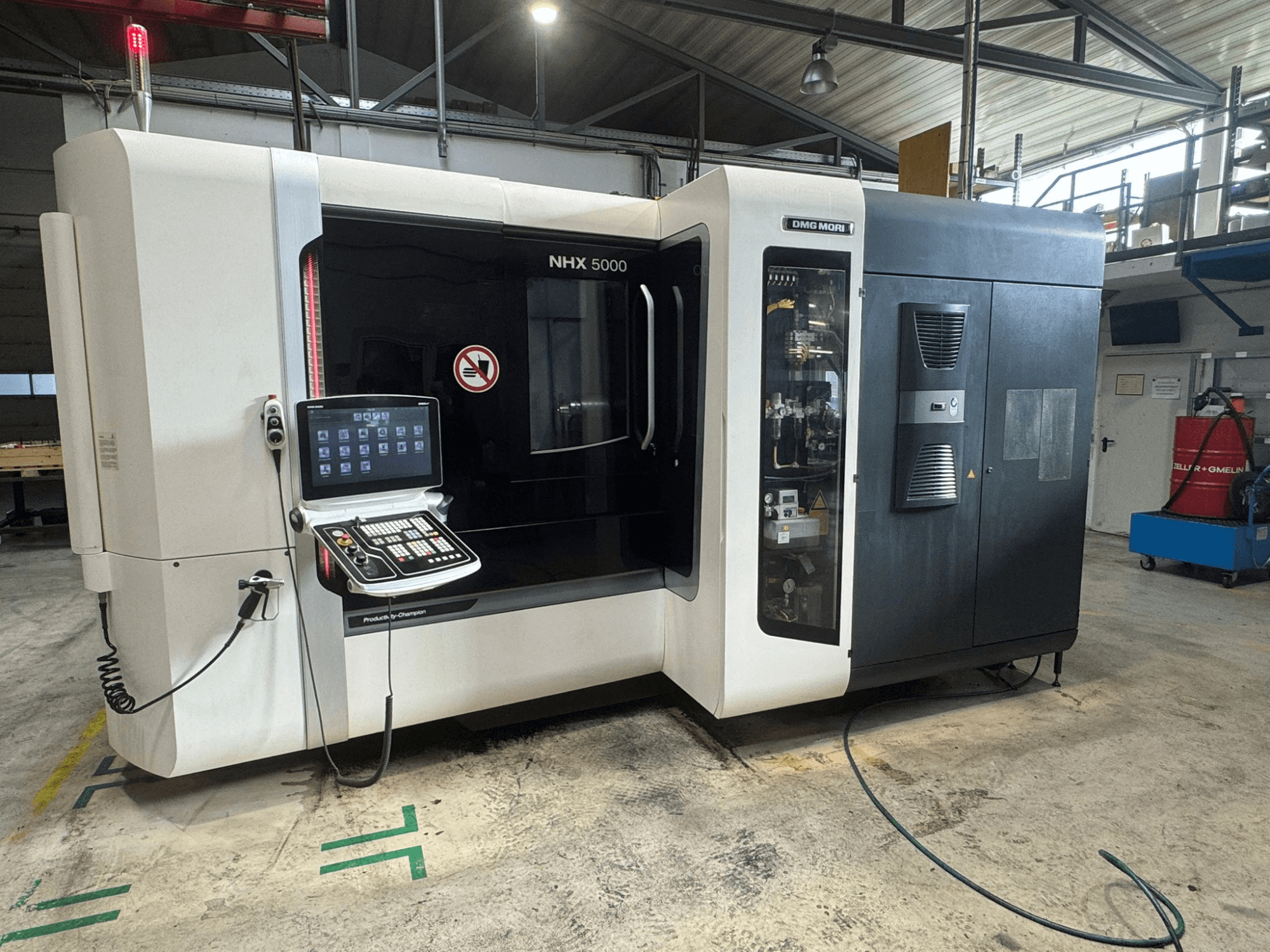 DMG MORI NHX 5000 horizontal machining centre, front view with control panel visible and safety indicators.