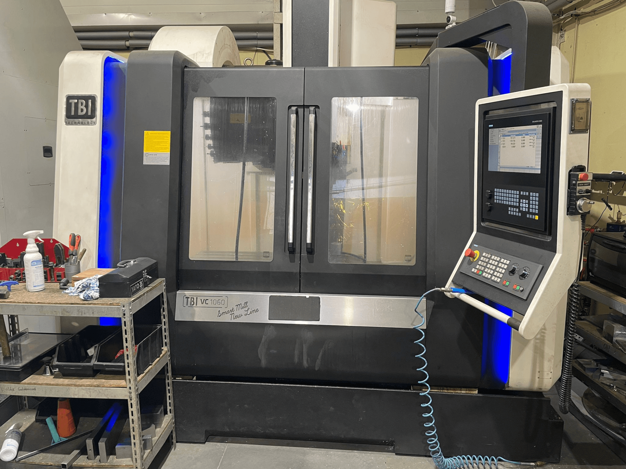 TBI VC 1060 HH Vertical Machining Centre, front view, showing control panel, dust cover, and illuminated blue accents.