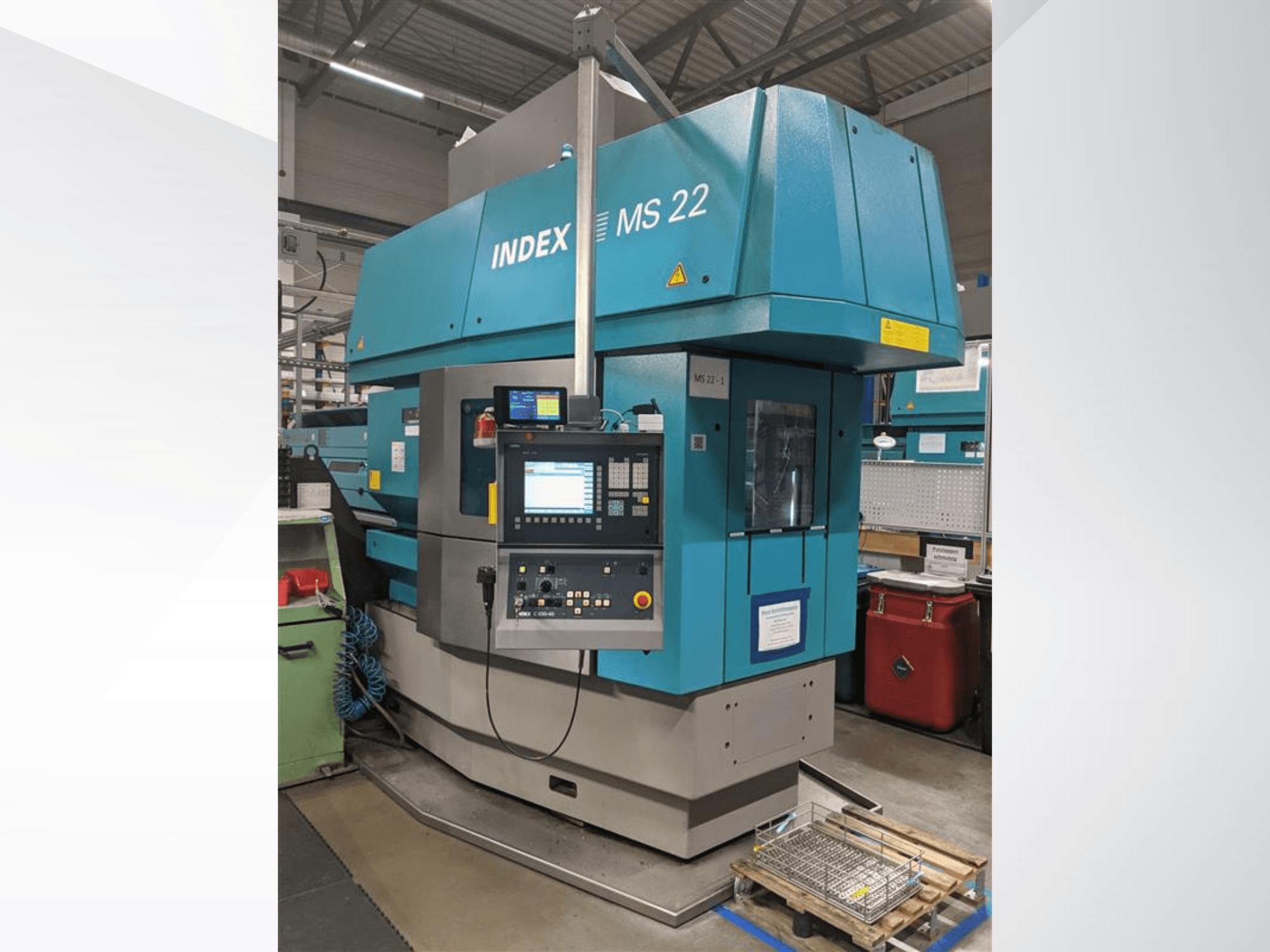 Multi-spindle turning machine Index MS 22 in a factory setting, front view showing control panel and blue exterior.