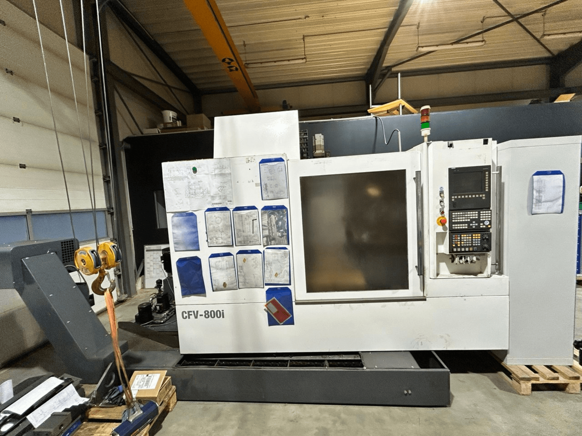 CFV-800i CNC machine shown in front view, with control panel, documents on side, and overhead crane in factory setting.