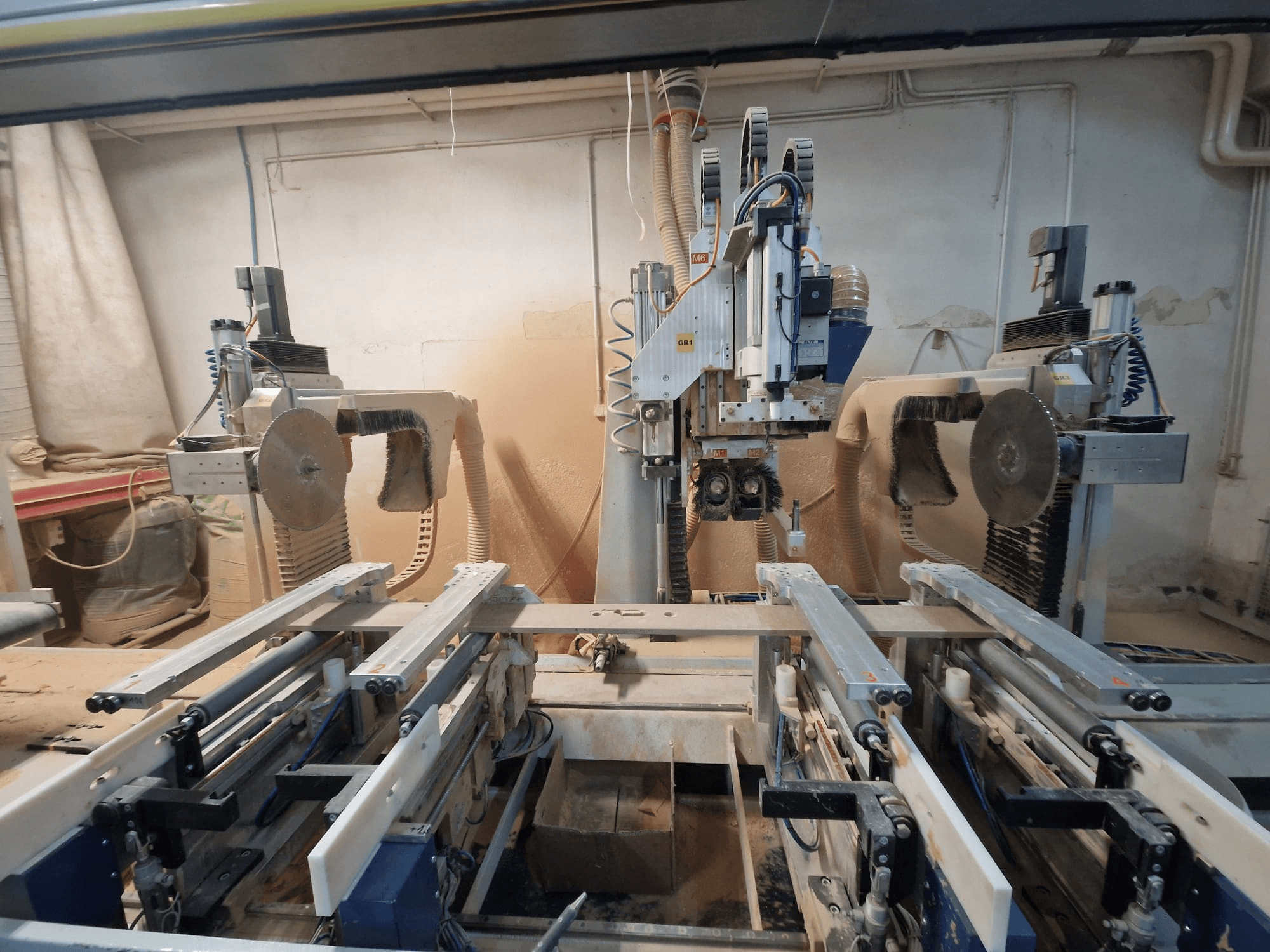 CNC machine with dual saw blades and rails, viewed from the front. Dust extraction systems visible, suitable for woodworking.