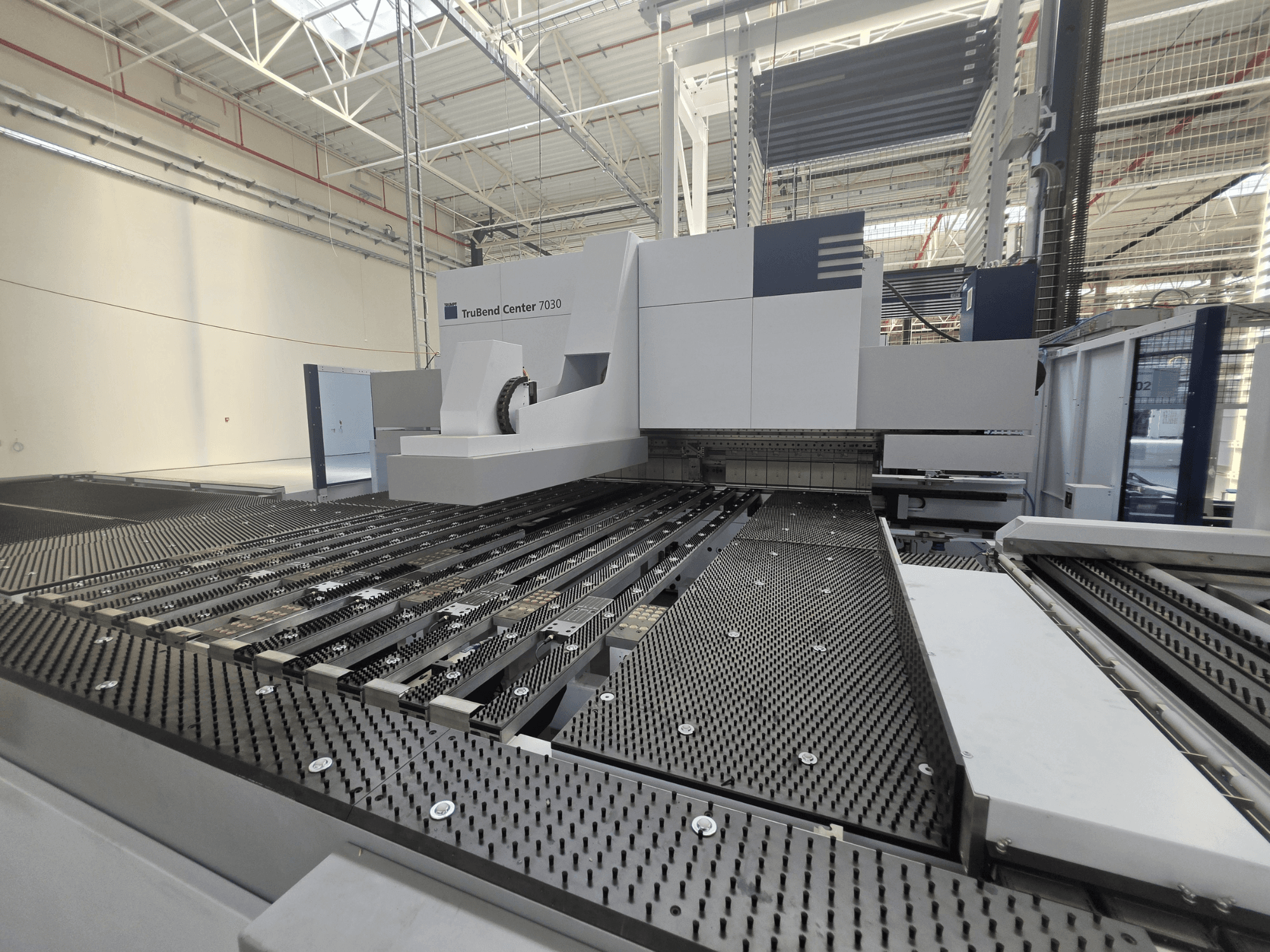 TRUMPF TruBend Center 7030 folding machine in a factory setting, front view showing the intricate worktable and bending arm.