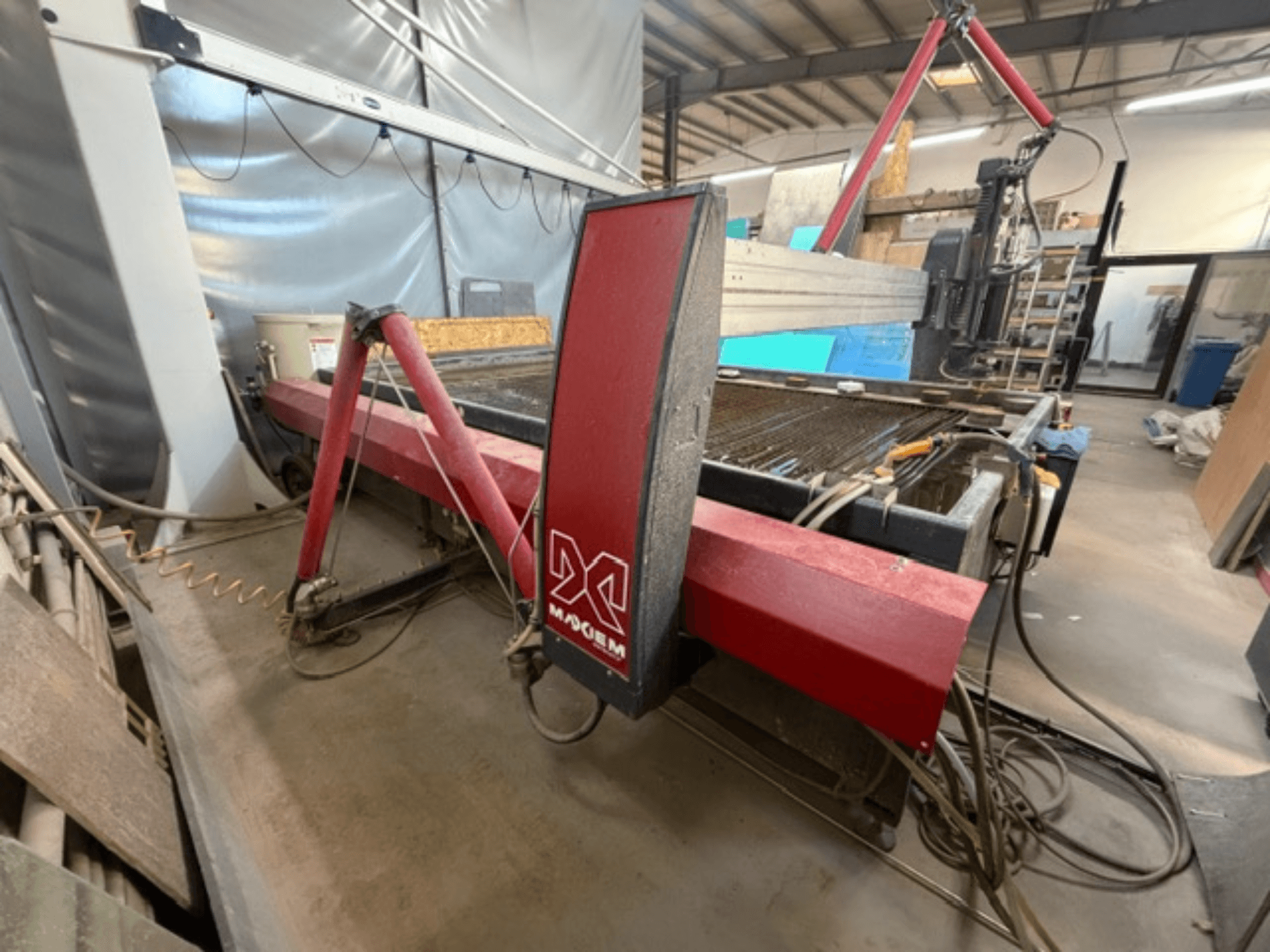 Red waterjet cutting machine from the brand X, viewed from the side, showing mechanical components and piping details.