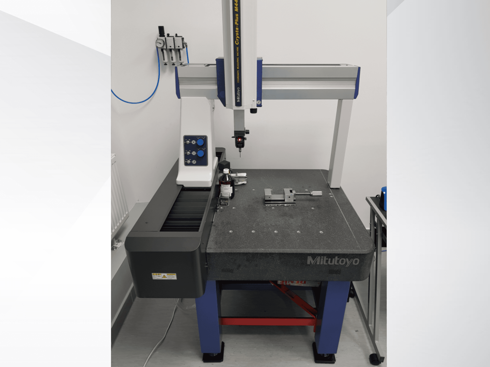 Mitutoyo Crysta-Plus M443 CMM in a front view, featuring measurement probe, control panel, and inspection table with fixtures.