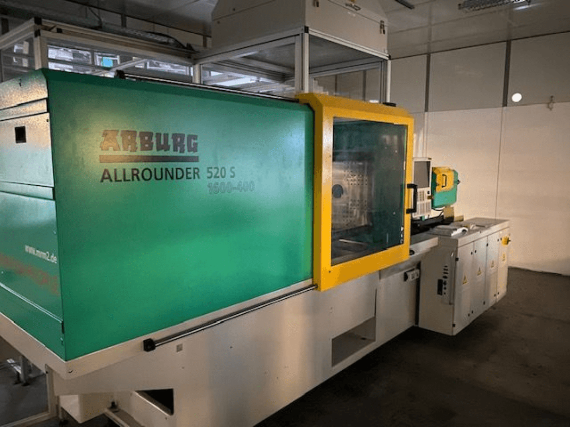 Arburg Allrounder 520 S injection molding machine, side view, featuring a green and yellow exterior, technical details visible.