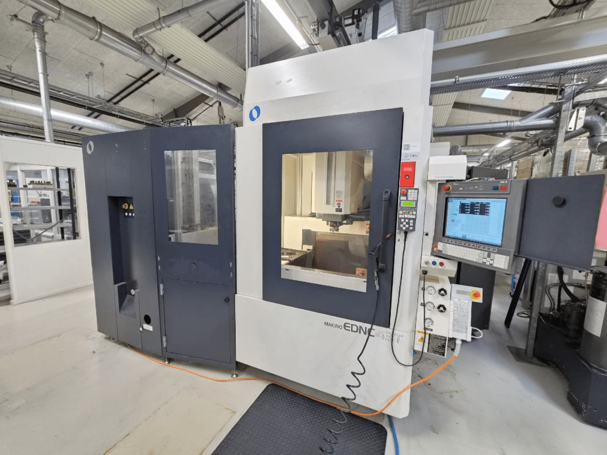 Front view of a Makino EDNC 43T die-sinking EDM machine, featuring Erowa Robot, controls, and visible workspace.