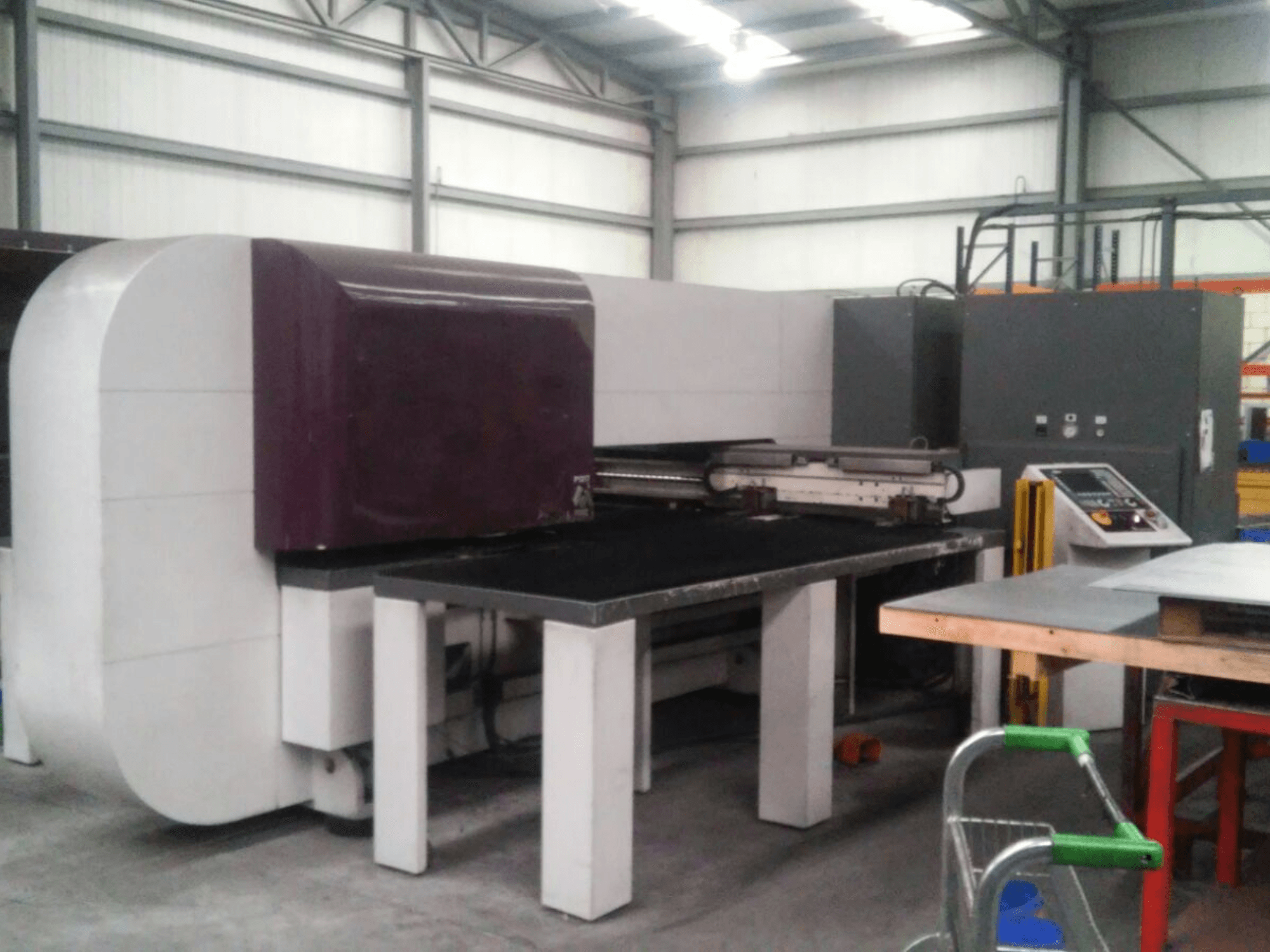 Purple industrial machine with a flat surface, side view, featuring controls and a sturdy base for operational tasks.