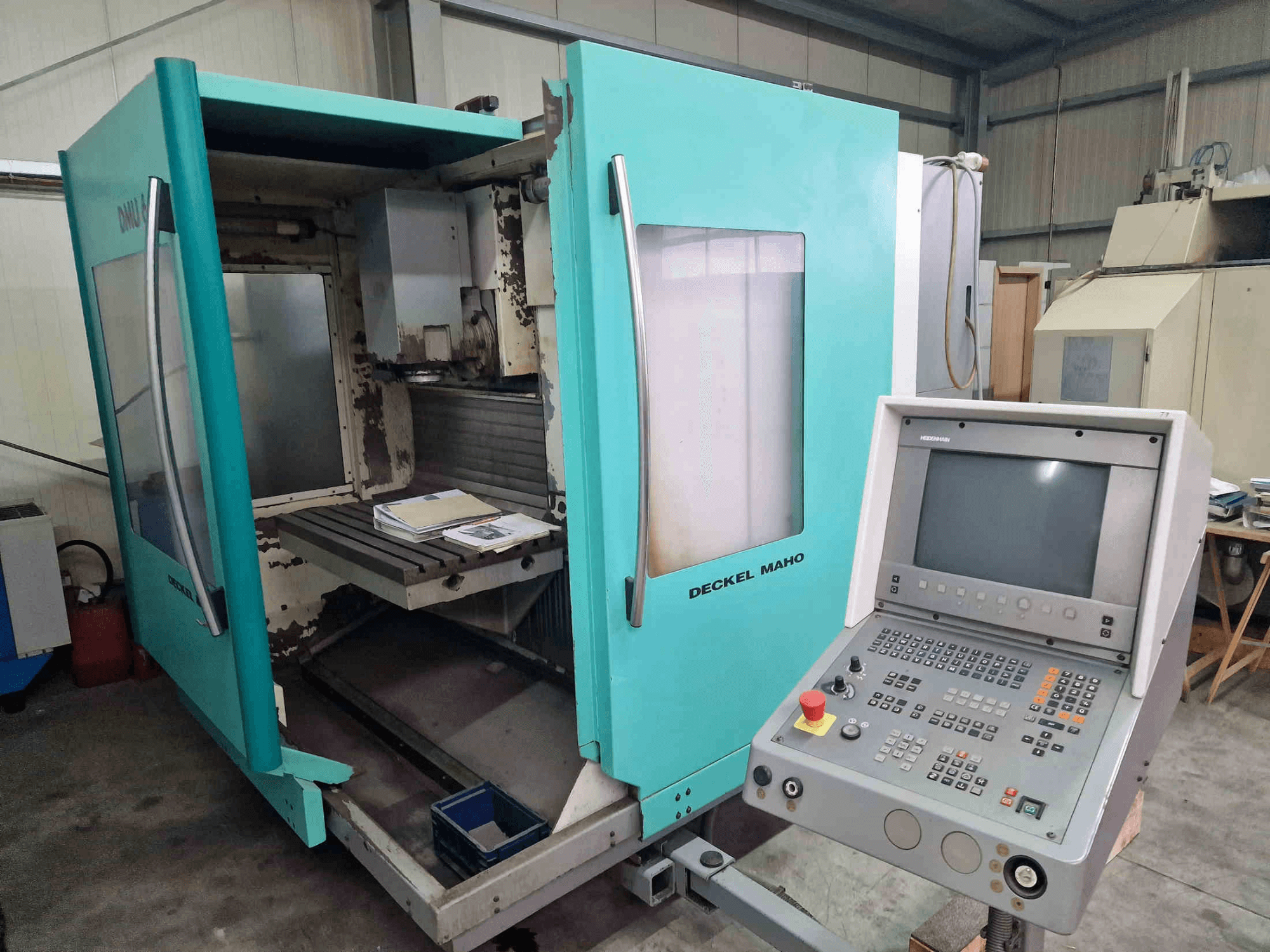 Front view of DECKEL MAHO DMU 60 E vertical machining center with an open door, revealing a work area and control panel.