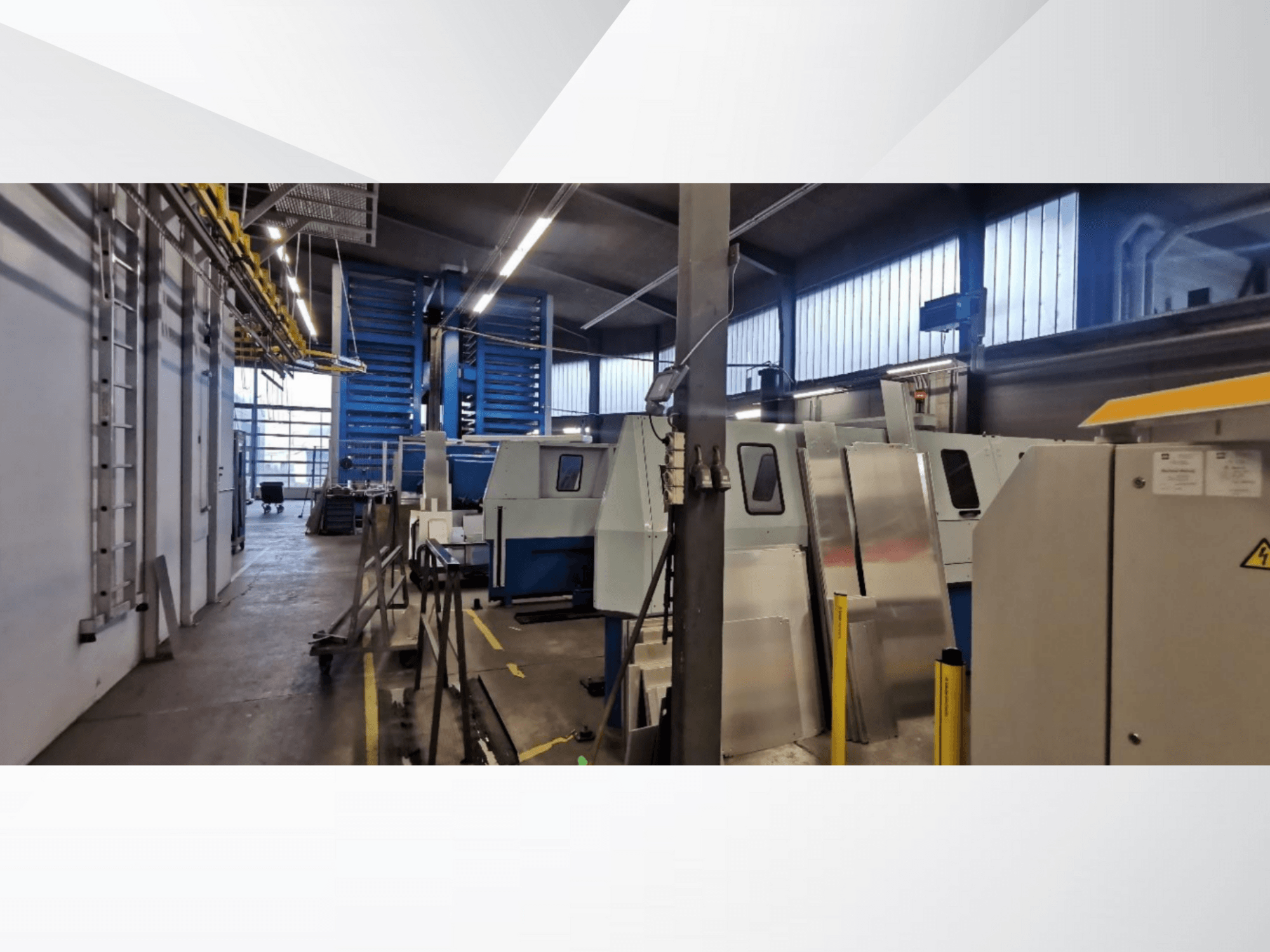 Industrial workshop scene featuring several machines and equipment in a side view, with metallic surfaces and visible safety fixtures.