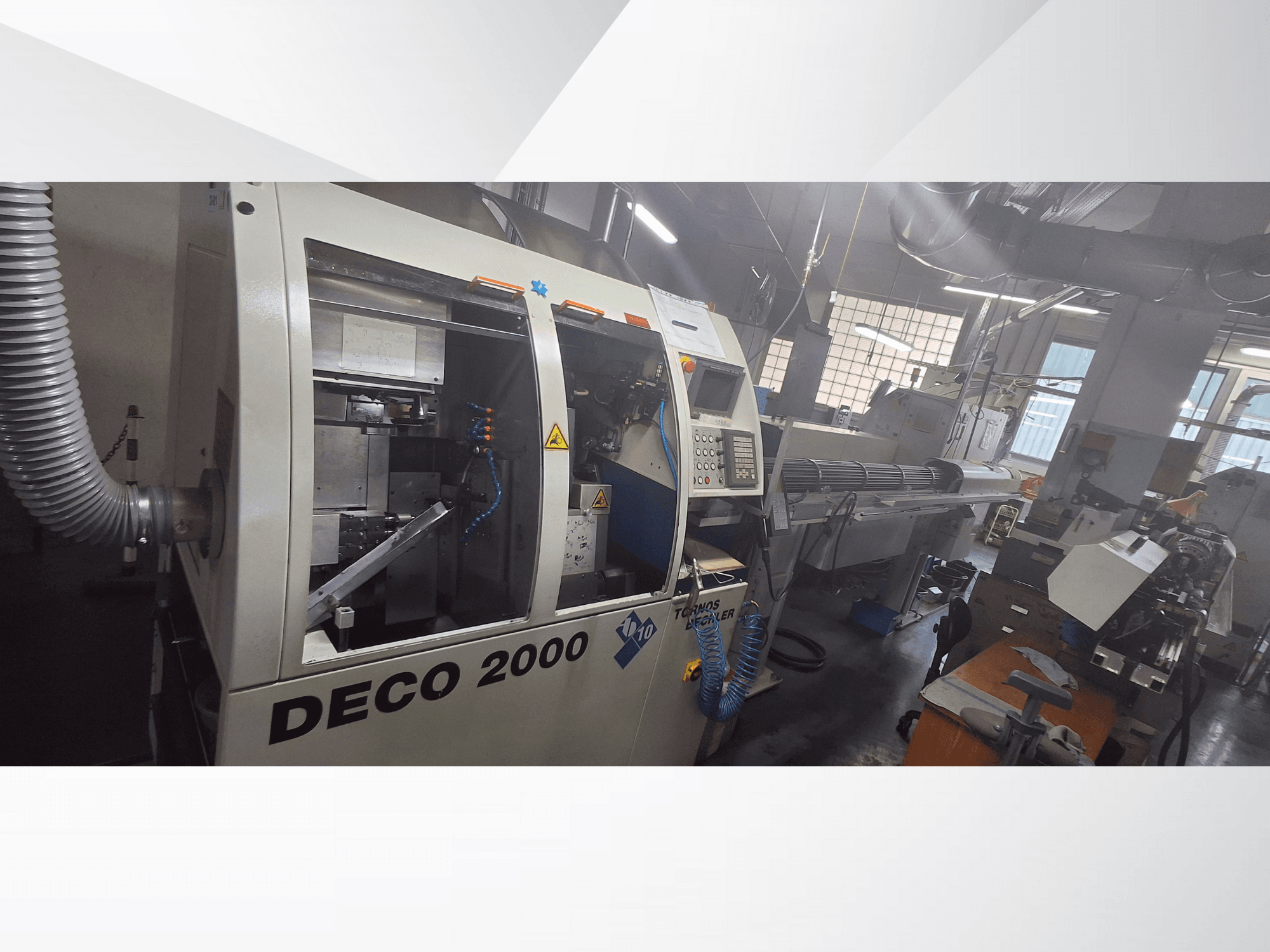DECO 2000 CNC machine in a workshop, front view, showcasing controls and a long workpiece setup on the right.