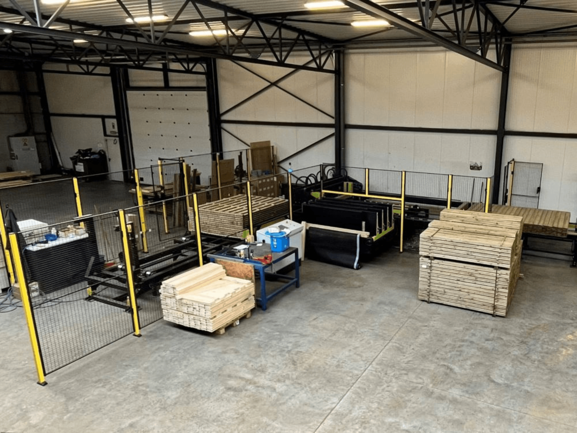 Complete production line (ISM ATM-01) for wood, viewed from above, showing machinery, wooden pallets, and safety fencing.