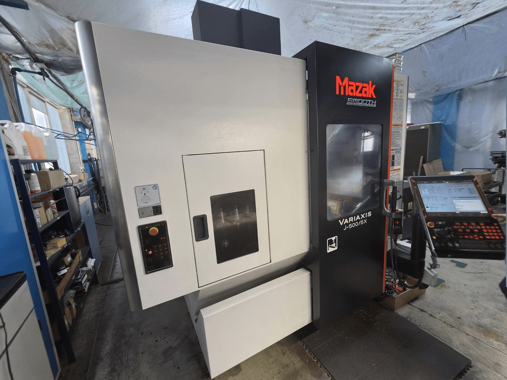 Mazak VARIAXIS J-500/5X vertical machining center in front view, featuring a control panel and large machining bay window.