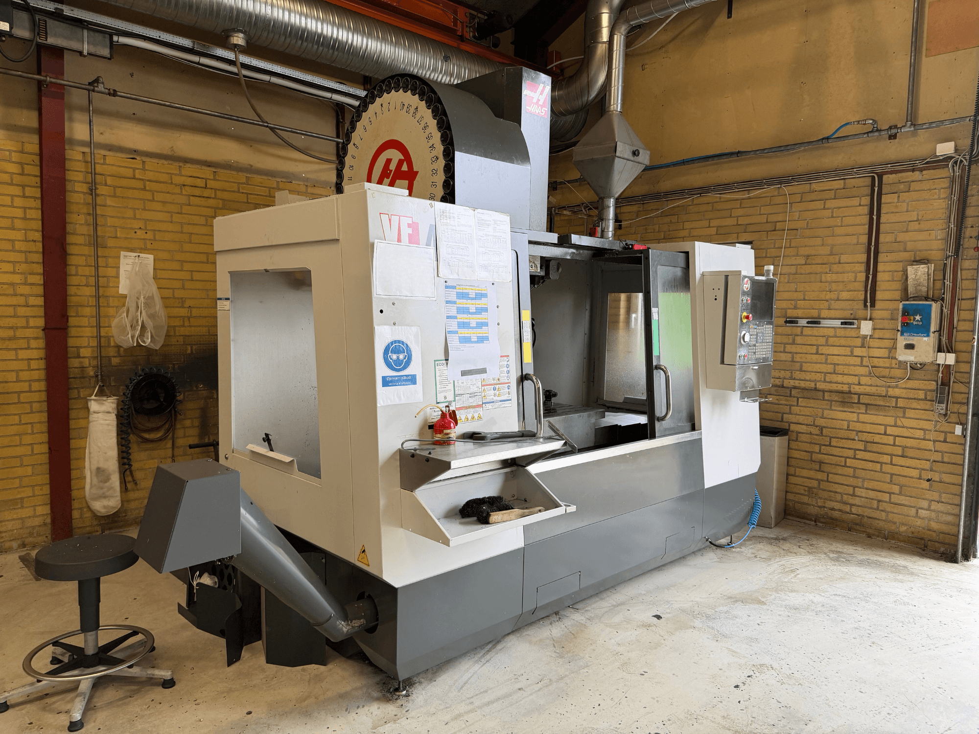 HAAS VF-4 Vertical Machining Centre, front view; features control panel, tool holder, and manufacturing setup in background.