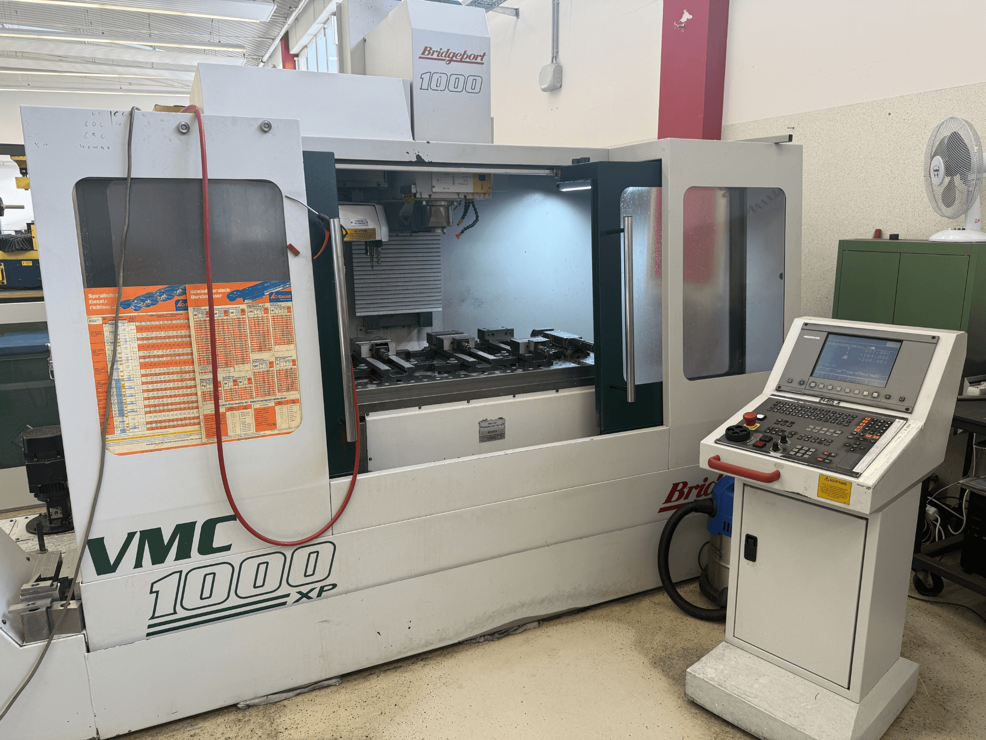 Front view of the Bridgeport VMC 1000 XP vertical machining center, showcasing controls, work area, and tool mountings.