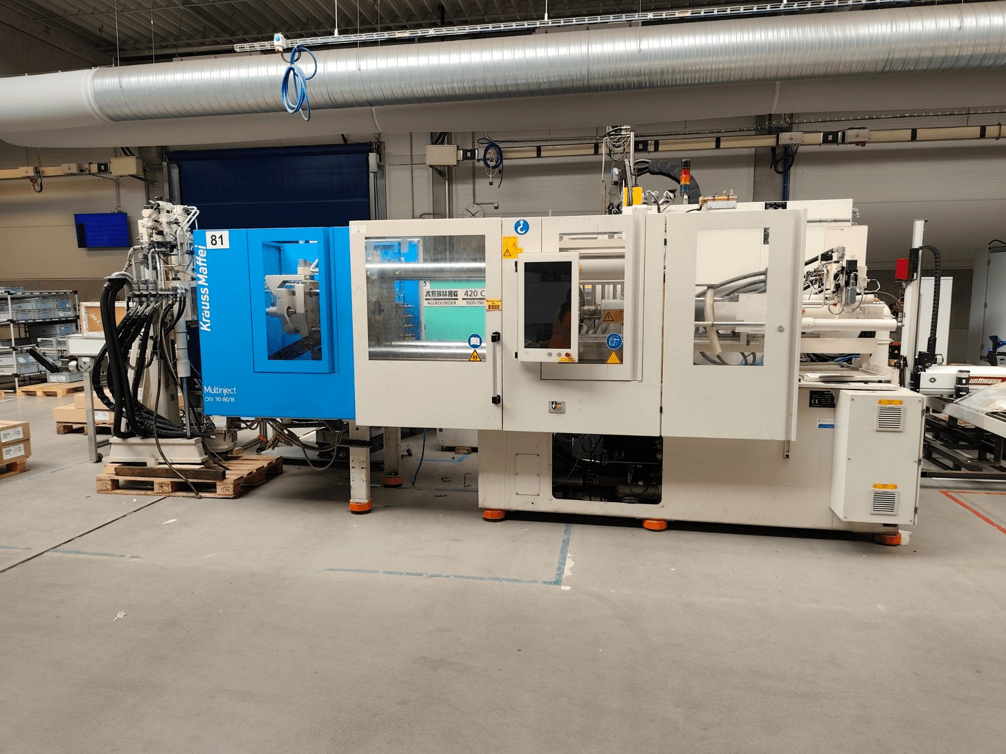 Krauss Maffei 110-180-180 CX V Hydraulic Injection Moulding Machine, side view, showcasing blue and white body, control panel, and connectors.