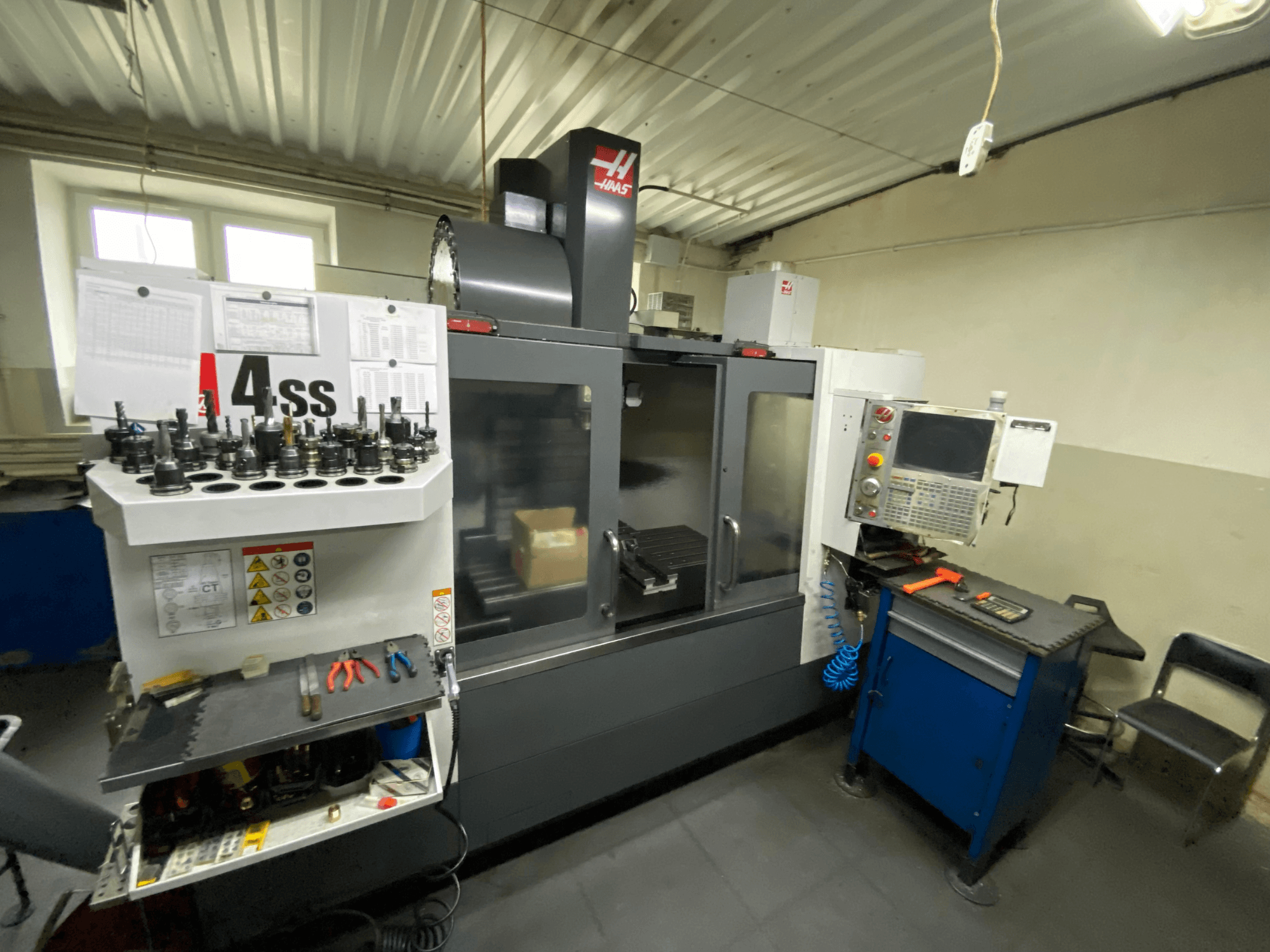 Haas VF-4SS vertical machining center, front view with tool holders and control panel. Featured tools and workspace visible.