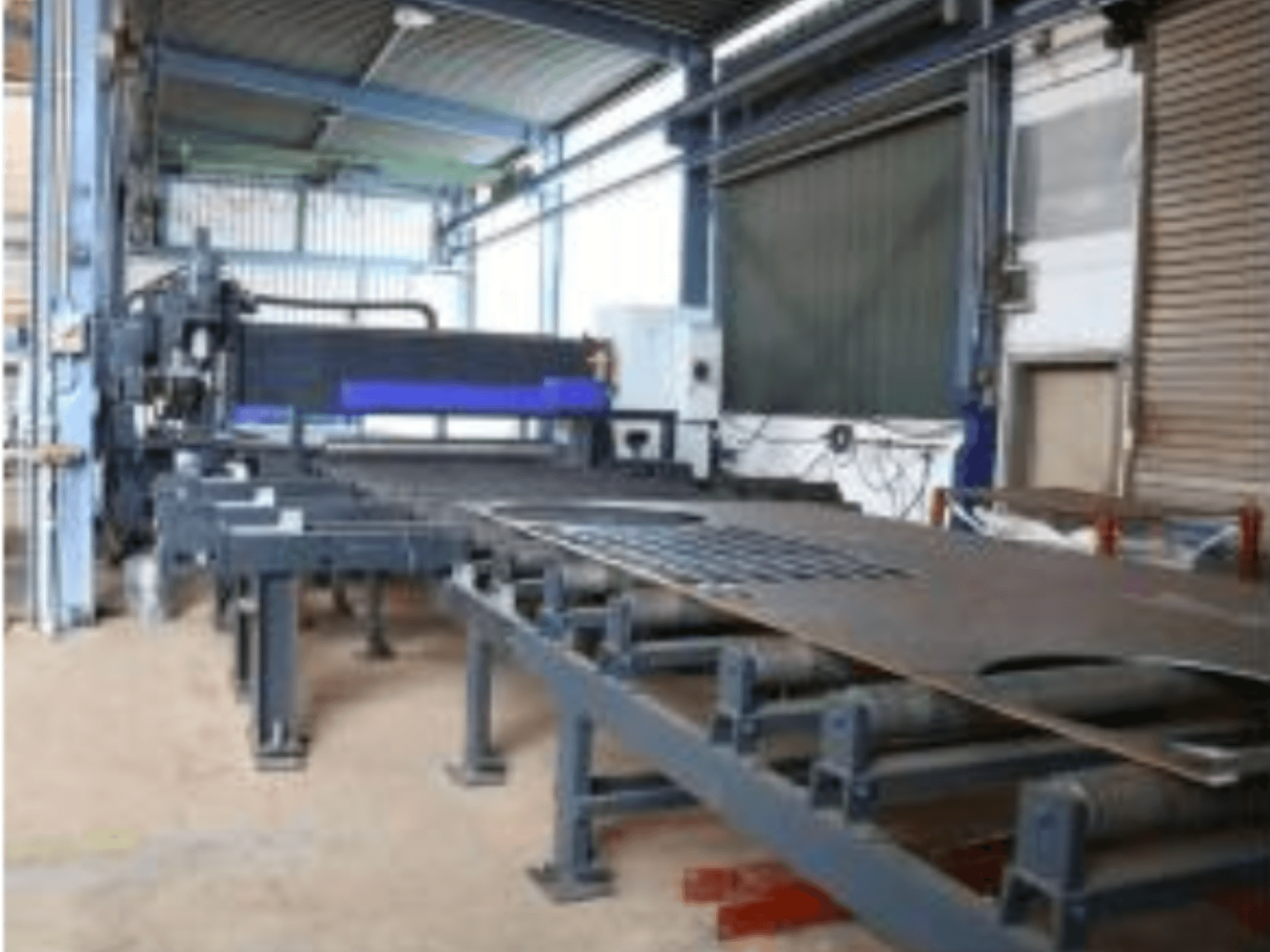 Behringer MAG EVO 420 sheet metal machine in a workshop, side view showing conveyor and cutting area.