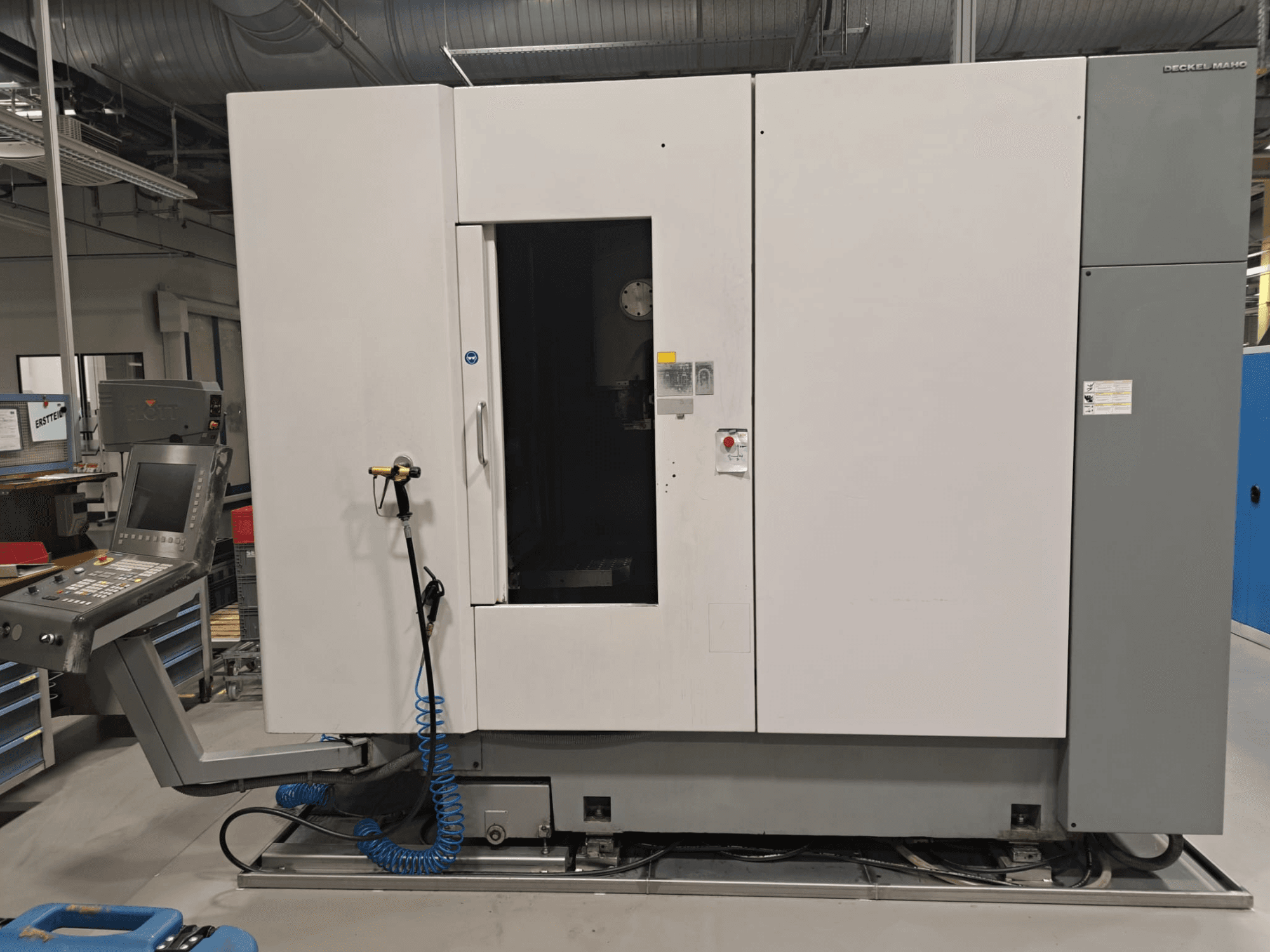 DECKEL MAHO DMP 60V vertical machining center, front view showing control panel and main body with an open door for accessibility.