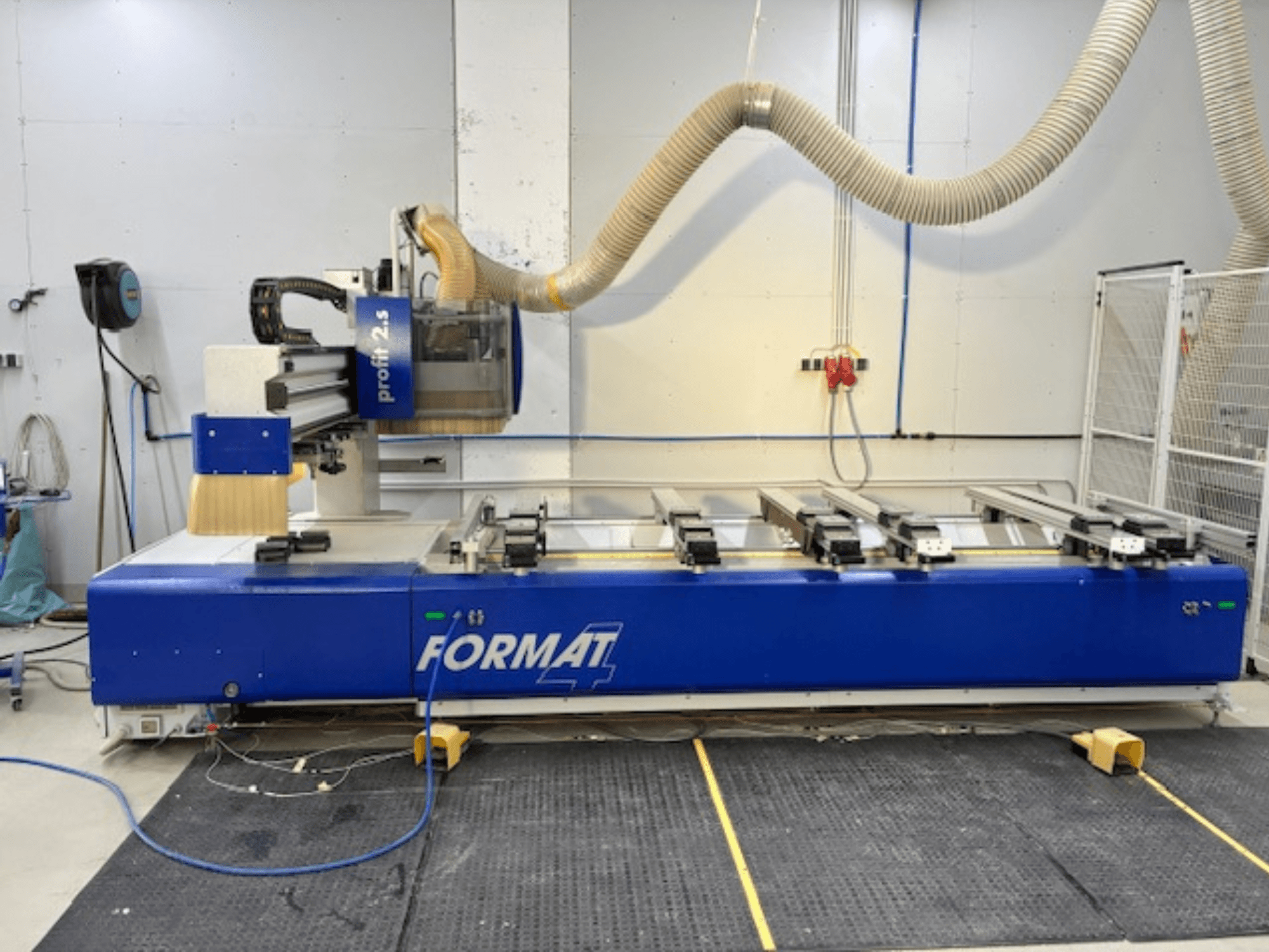 Blue FORMAT 4 CNC router, model Profit 2.5, side view showing cutting area and dust extraction system, on a rubber mat.